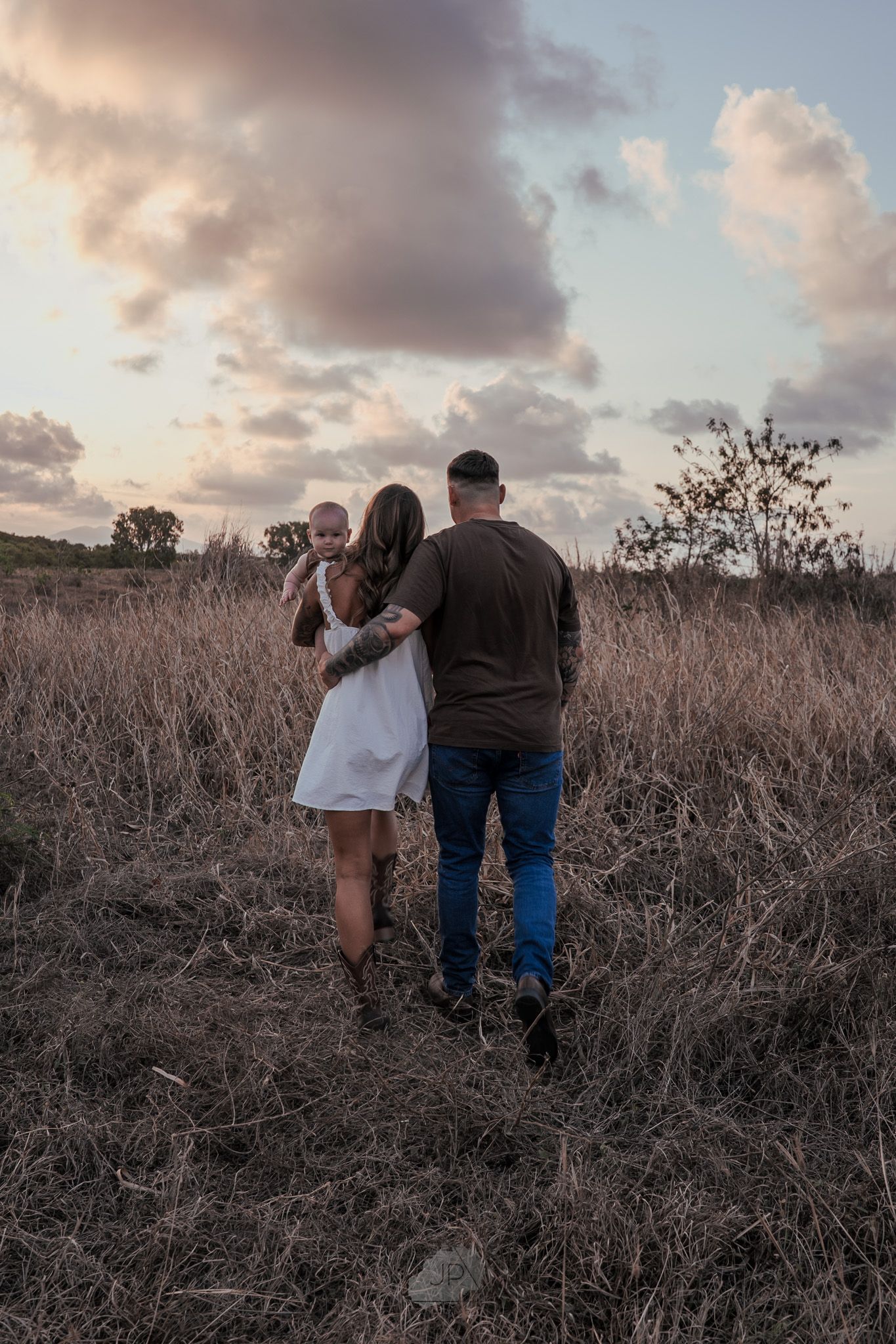 A couple walks together through a golden field at sunset, creating a romantic silhouette against the dusky sky.