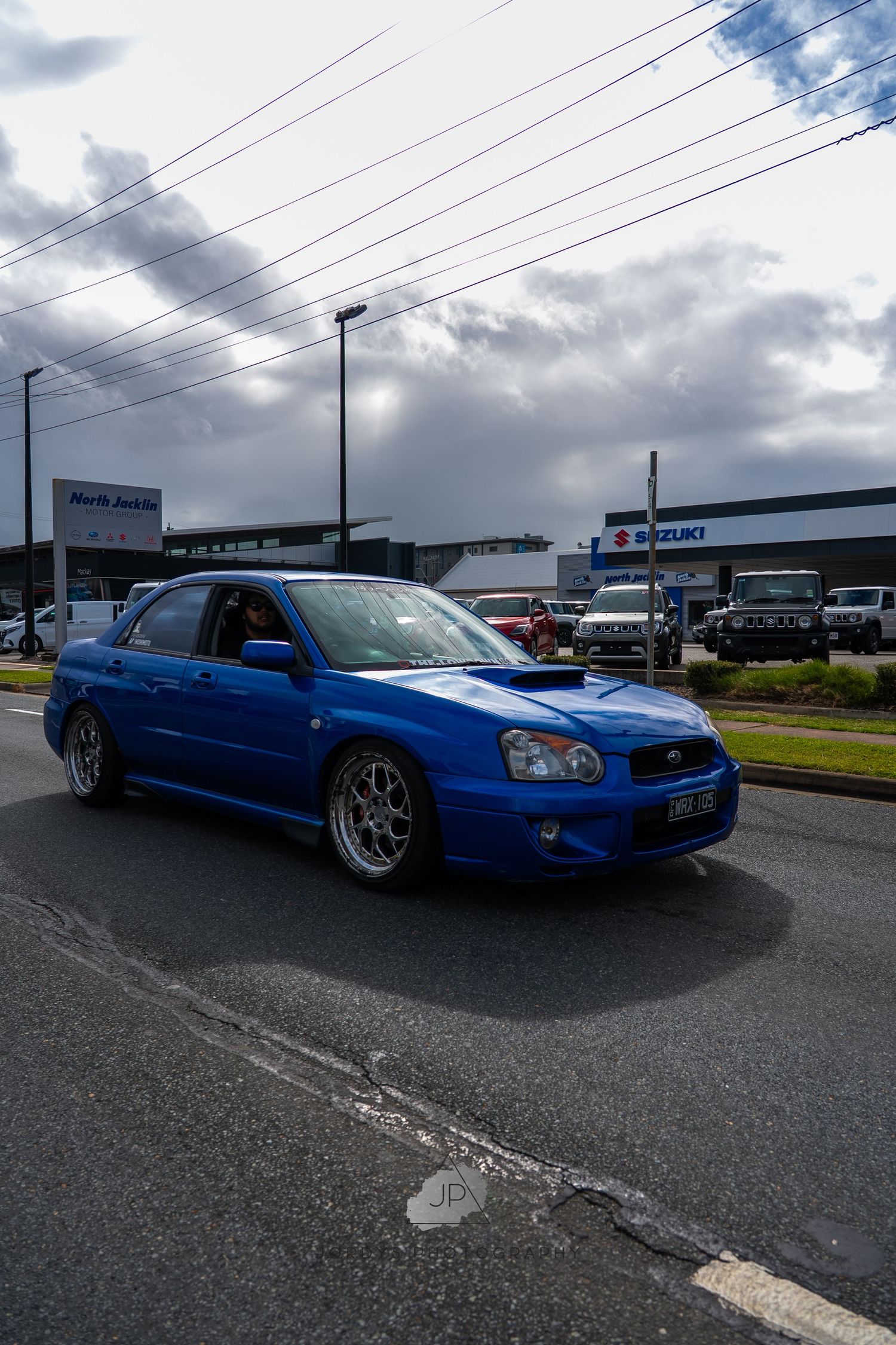 A customized blue Subaru WRX with lowered suspension and aftermarket modifications photographed from multiple angles.
