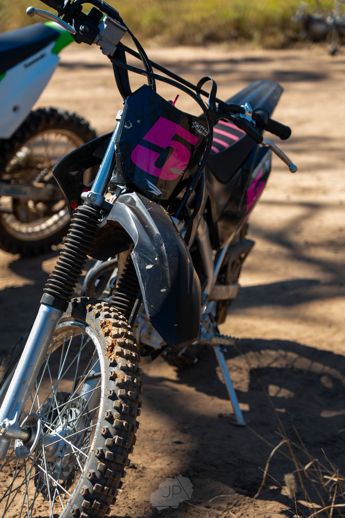 Close-up detail shots of a dirt bike's knobby tire, suspension, and mechanical components in outdoor lighting.