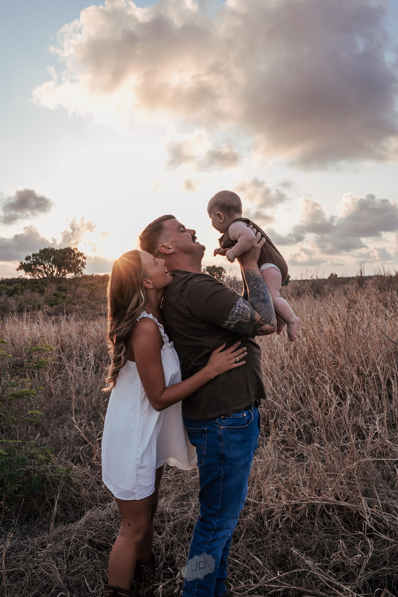 Couple sharing intimate moments in a golden field at sunset during a romantic photo session.