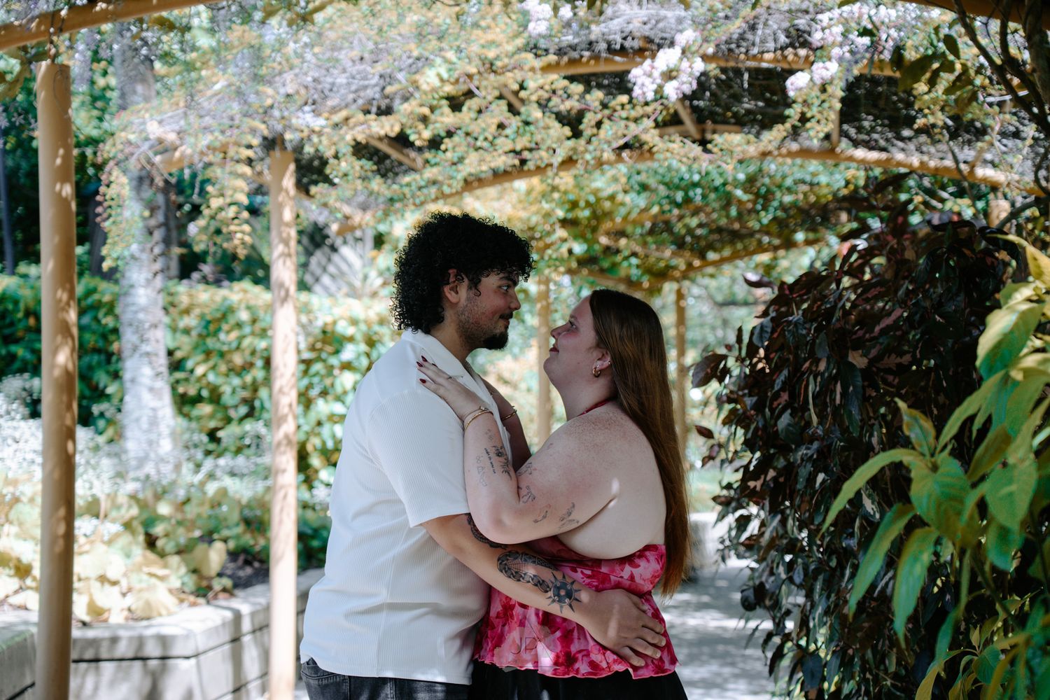 A couple shares a romantic moment under blooming cherry blossom trees in a spring garden setting.