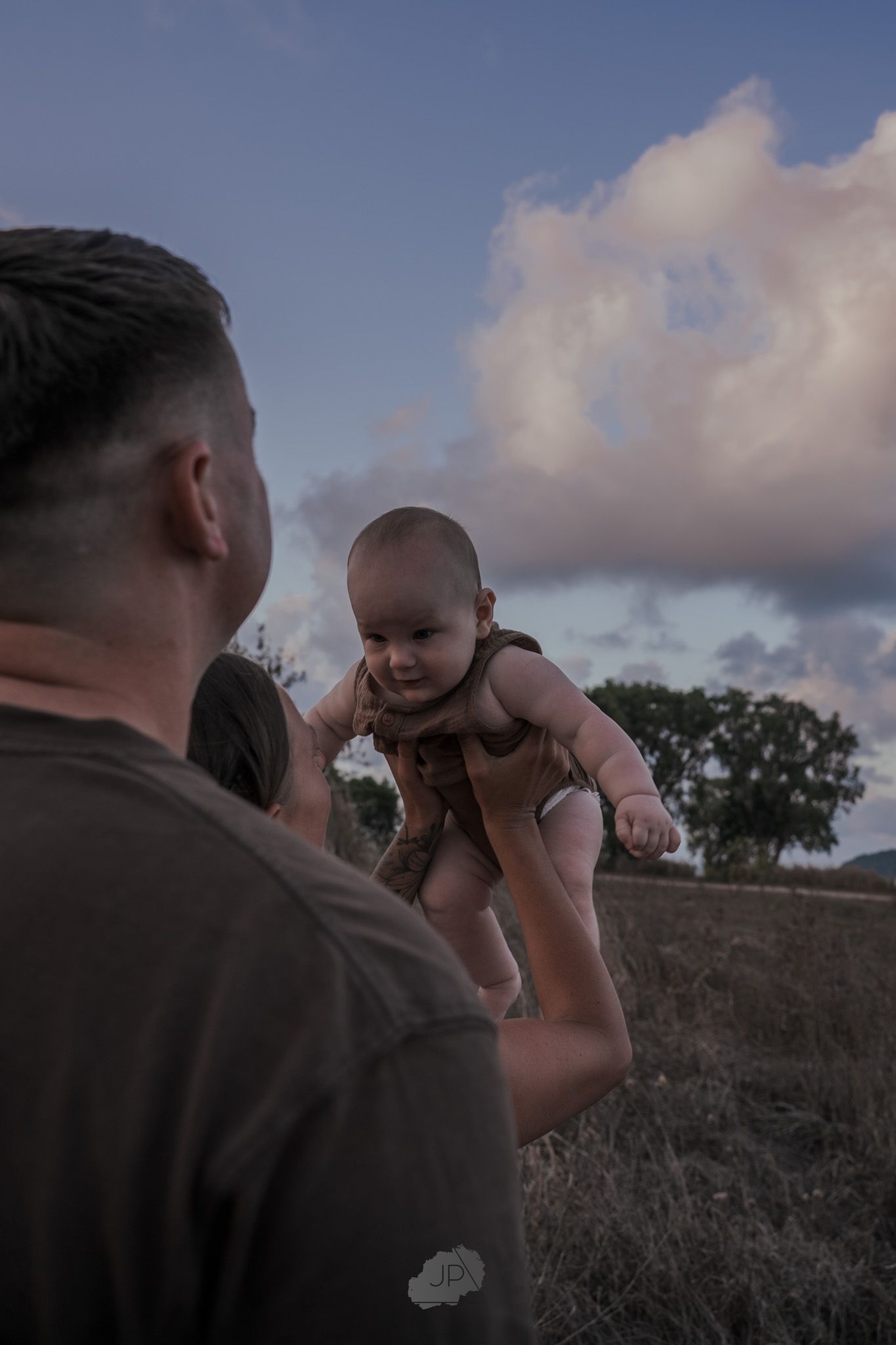 A series of candid outdoor photos showing tender moments between a parent and baby against a cloudy sky at sunset.