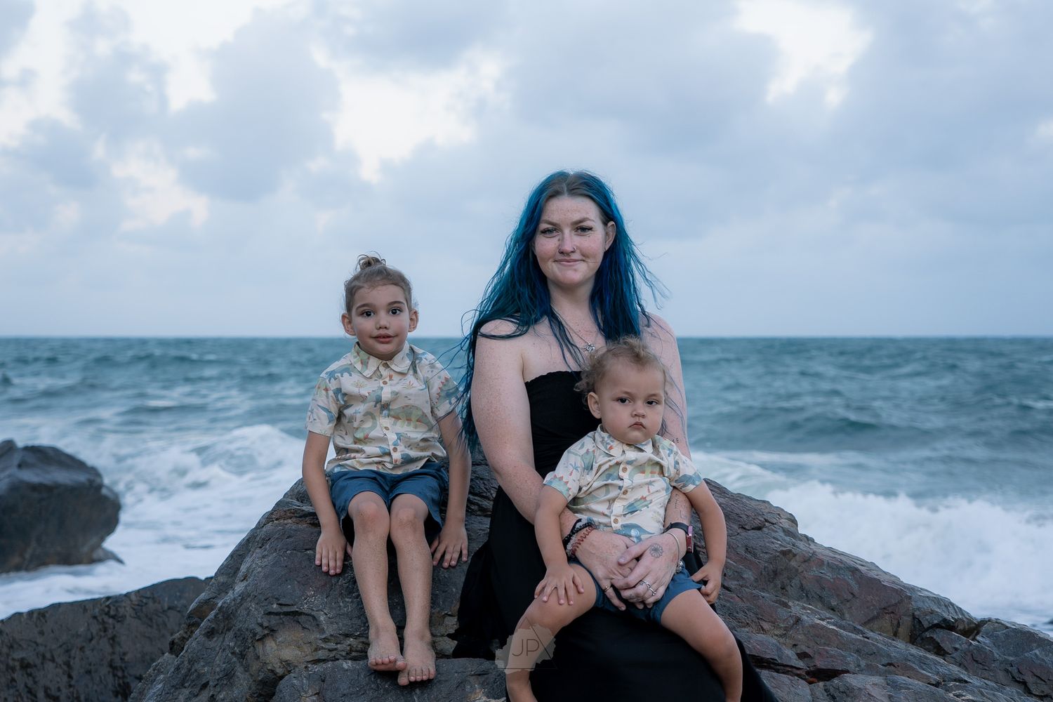 Family enjoying a day at a rocky beach with crashing waves and ocean views.