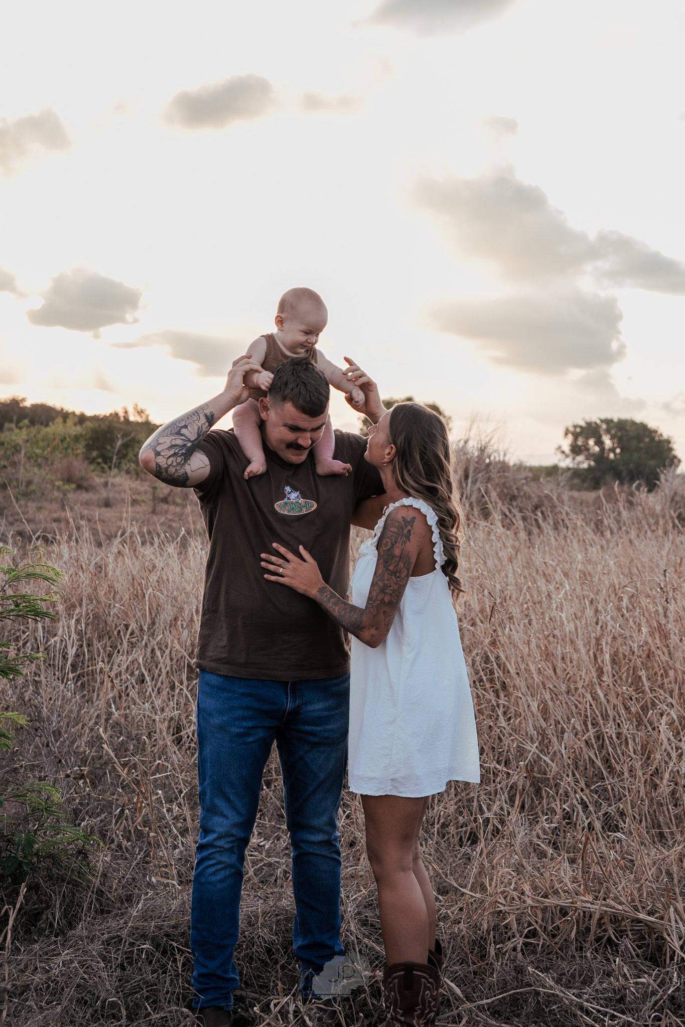 A family shares a tender moment together in a field of tall grass during sunset.