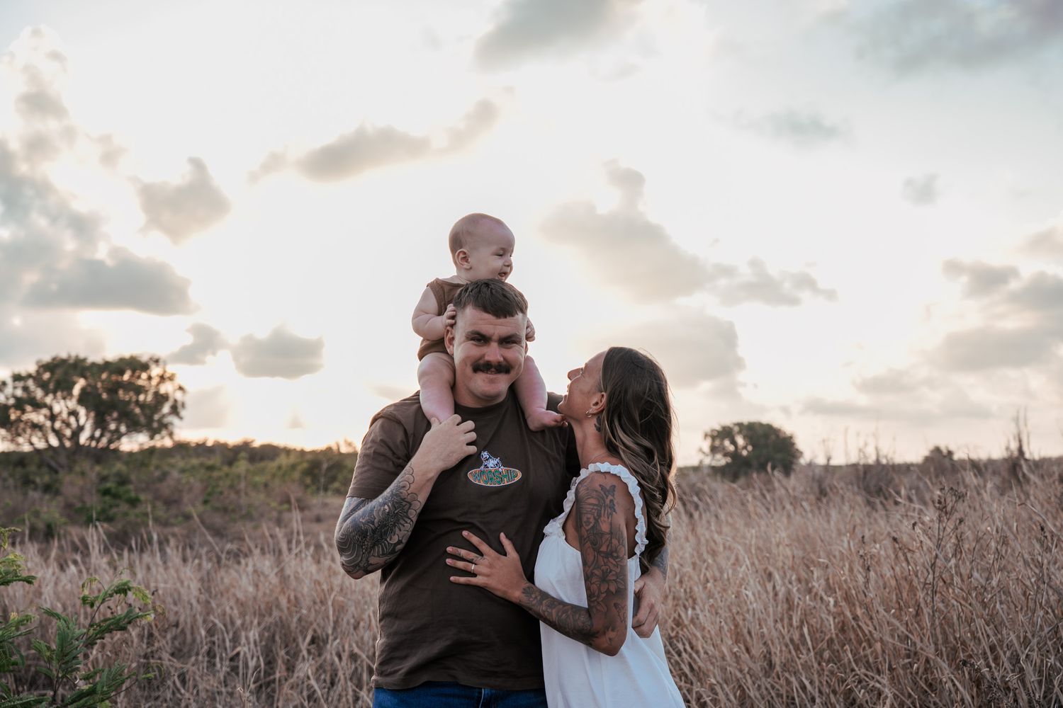 A family shares tender moments together in a golden field at sunset.