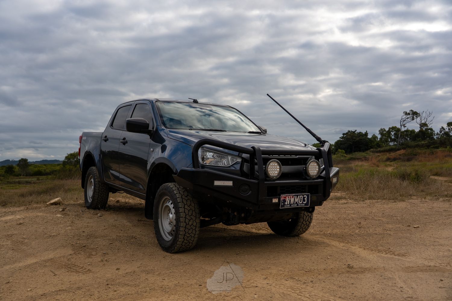 Black Ford Ranger pickup truck with bull bar parked on dirt terrain under cloudy sky.