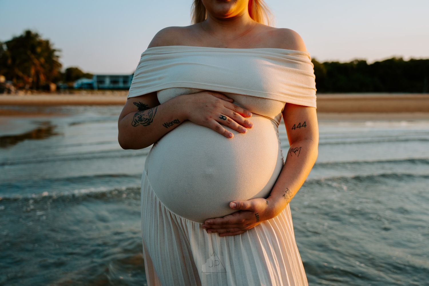A series of maternity photos showing a pregnant figure in a white dress standing by the ocean at sunset.