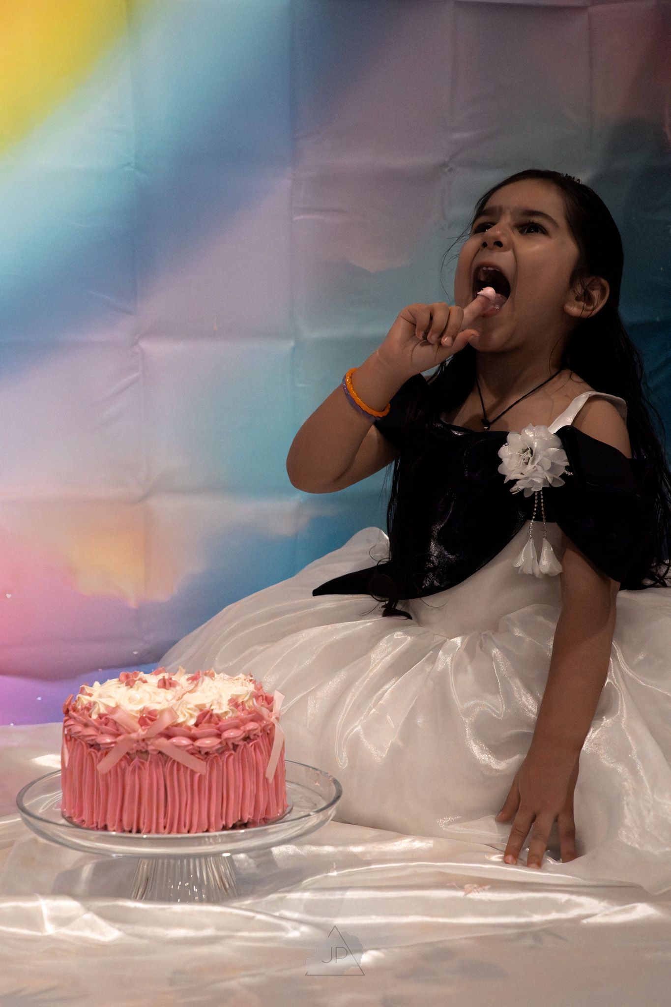 A sequence of photos showing someone in a white dress eating pink birthday cake during a photo shoot.