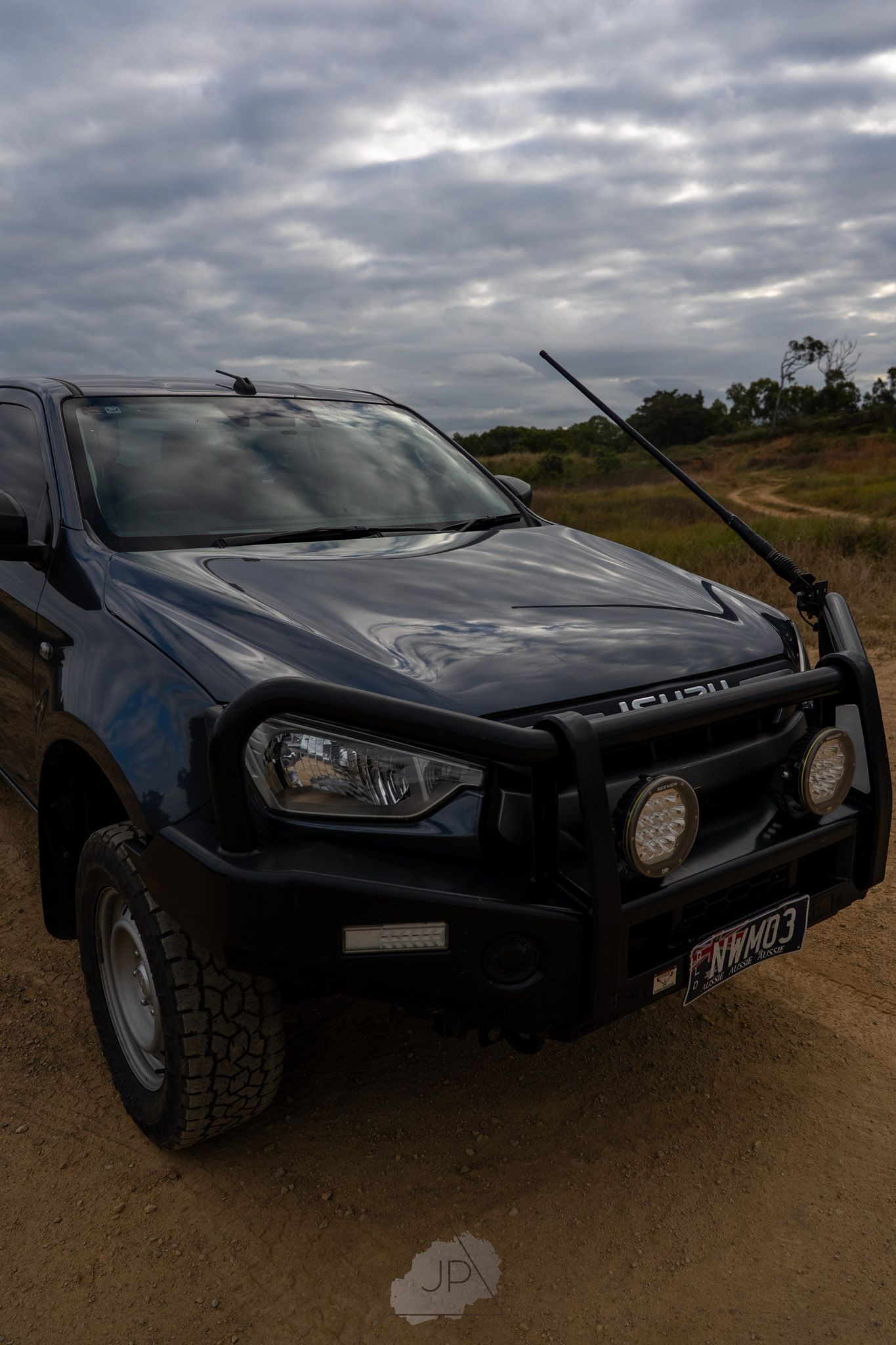 A series of black Isuzu vehicle photos showing various angles of the front end under dramatic cloudy skies.