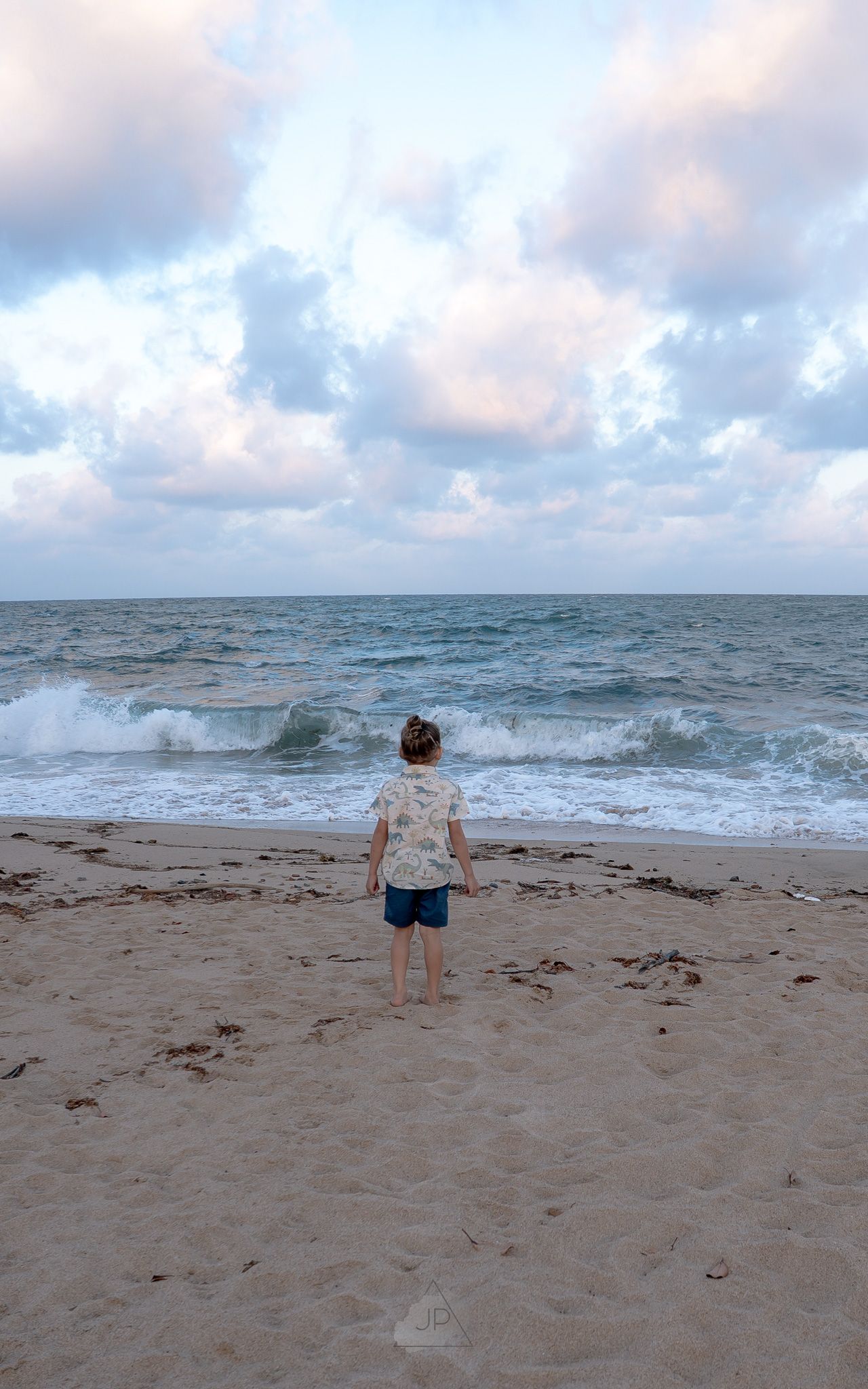 A sequence of four beach photos shows a person approaching and being splashed by an incoming ocean wave on a cloudy day.