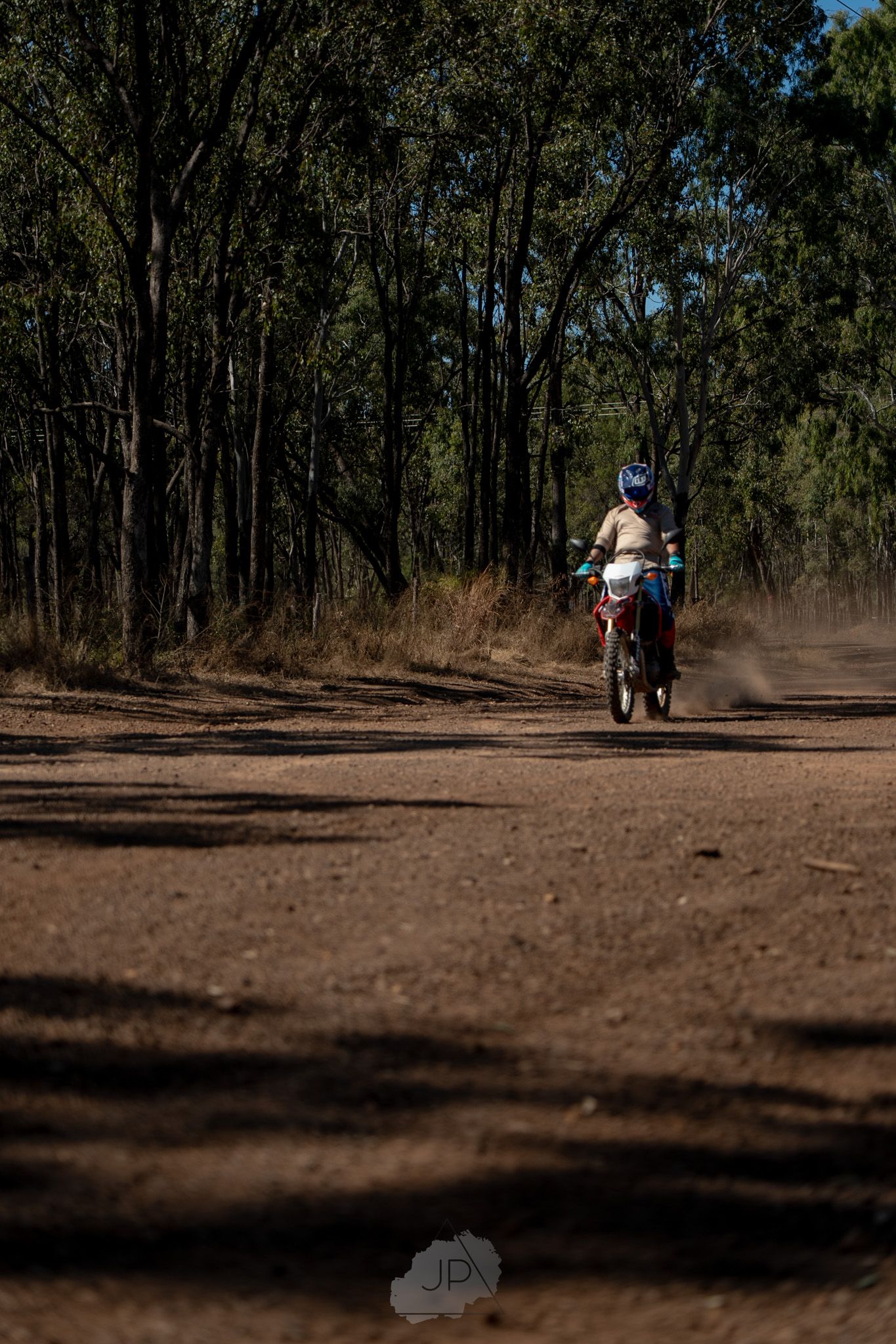 Sequence of ATV riding through dusty dirt trail in wooded area with long shadows cast across the ground.