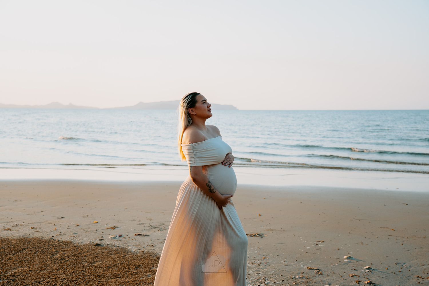 Romantic beach photoshoot featuring a couple in light flowy clothing against an ocean backdrop.