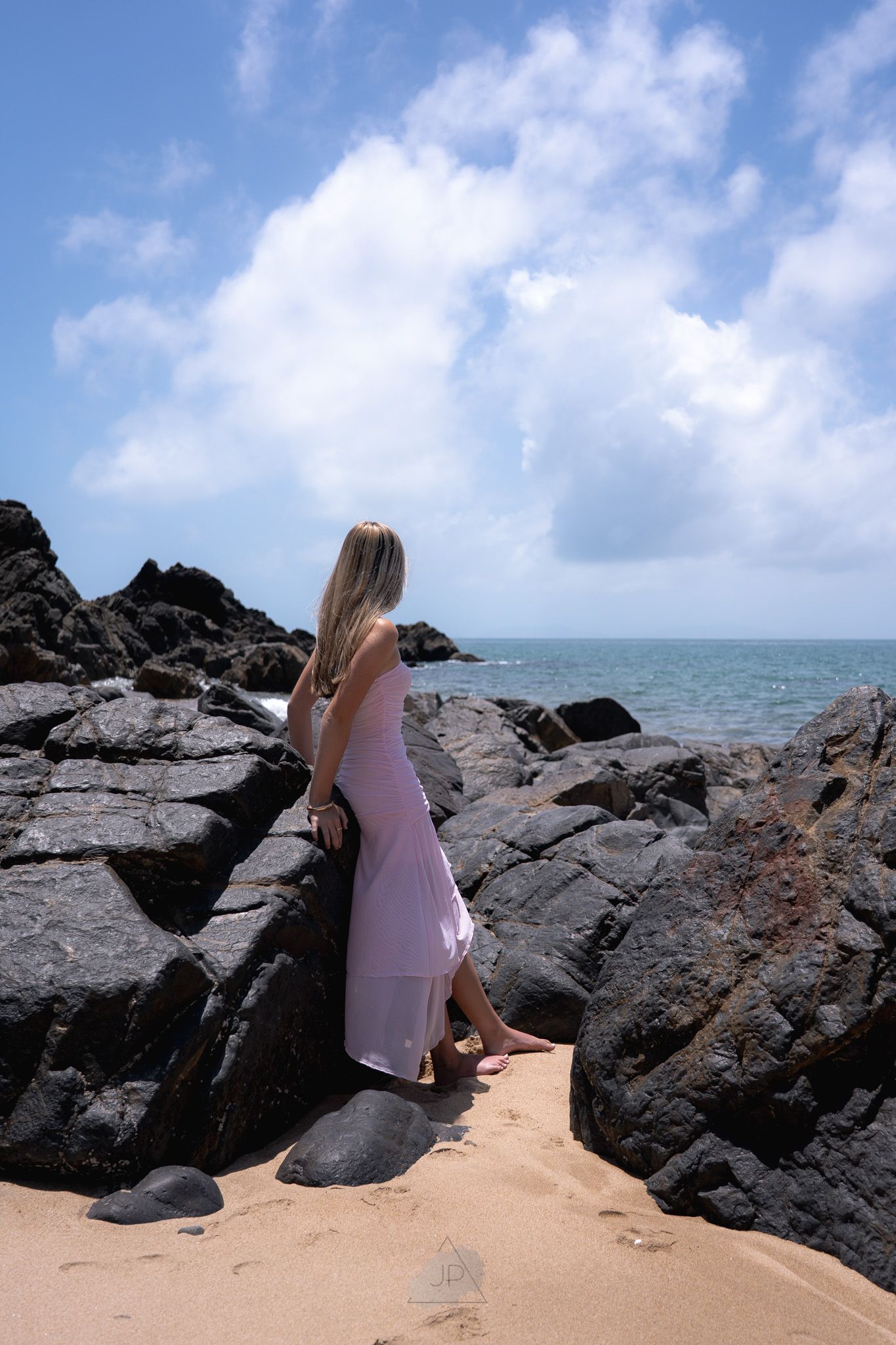 A sequence of images showing a sandy beach with dark rocky outcrops against a blue ocean horizon.