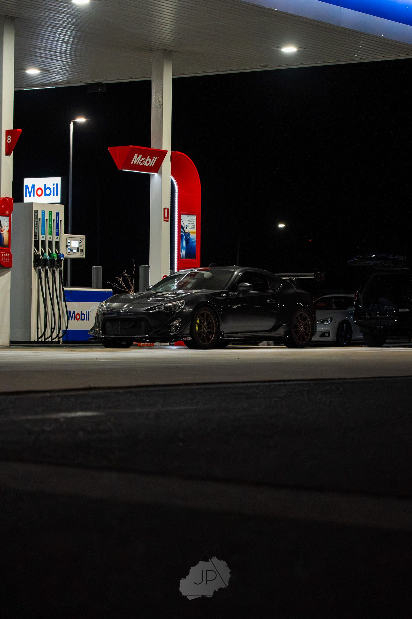 A Mobil gas station illuminated at night with bright overhead lights and multiple fuel pumps visible.