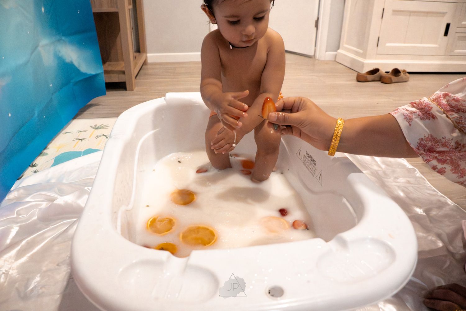 Child and adult hands working together to shape orange dough on a white surface during a baking activity.