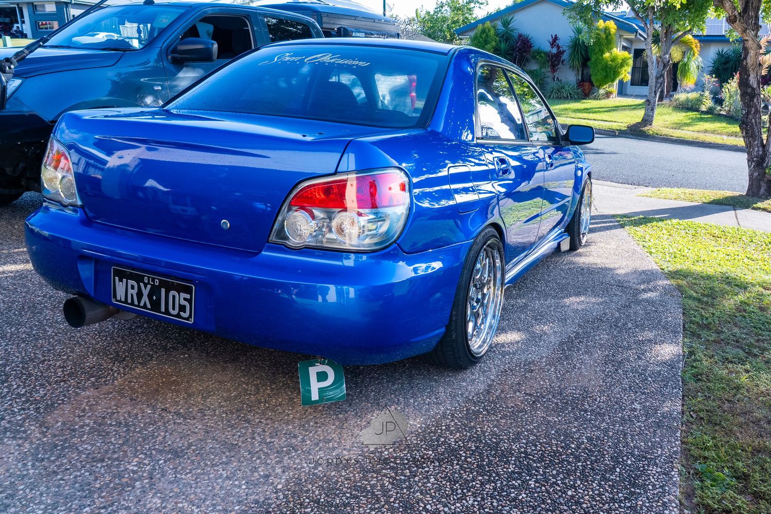 A bright blue modified Subaru Impreza WRX STI parked on gravel showcasing its custom performance upgrades and styling.