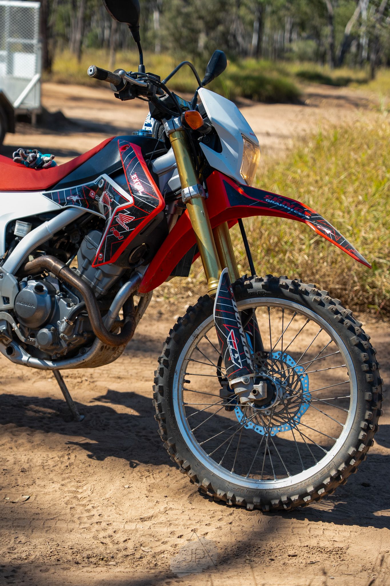 Close-up shots of dirt bike front wheel and tire tread on off-road trail showing knobby tire pattern and suspension details.
