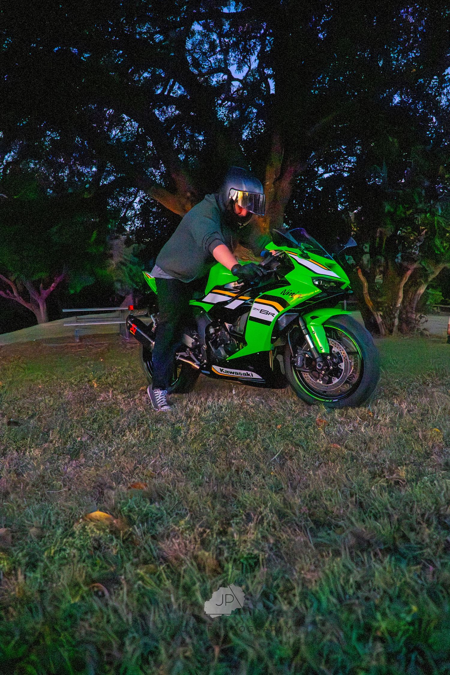 A green motorcycle topples over on a grassy slope at dusk in a sequential series of action shots.