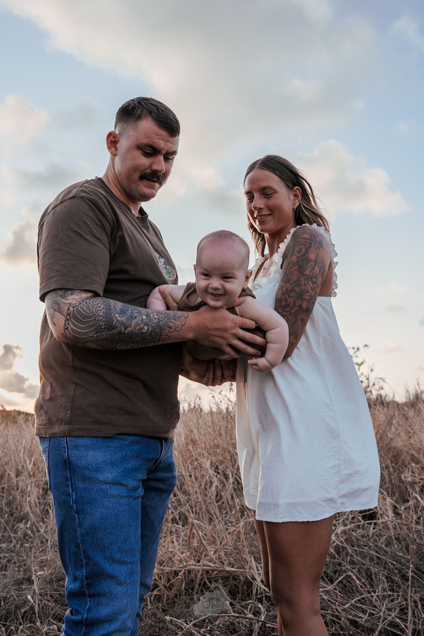 Candid family photos show joyful interactions and hugs in a golden field during sunset.