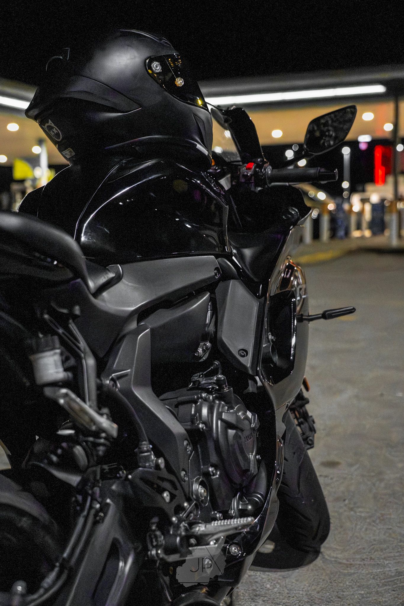 Black motorcycle details shown from multiple angles in low light parking garage setting with dramatic shadows.