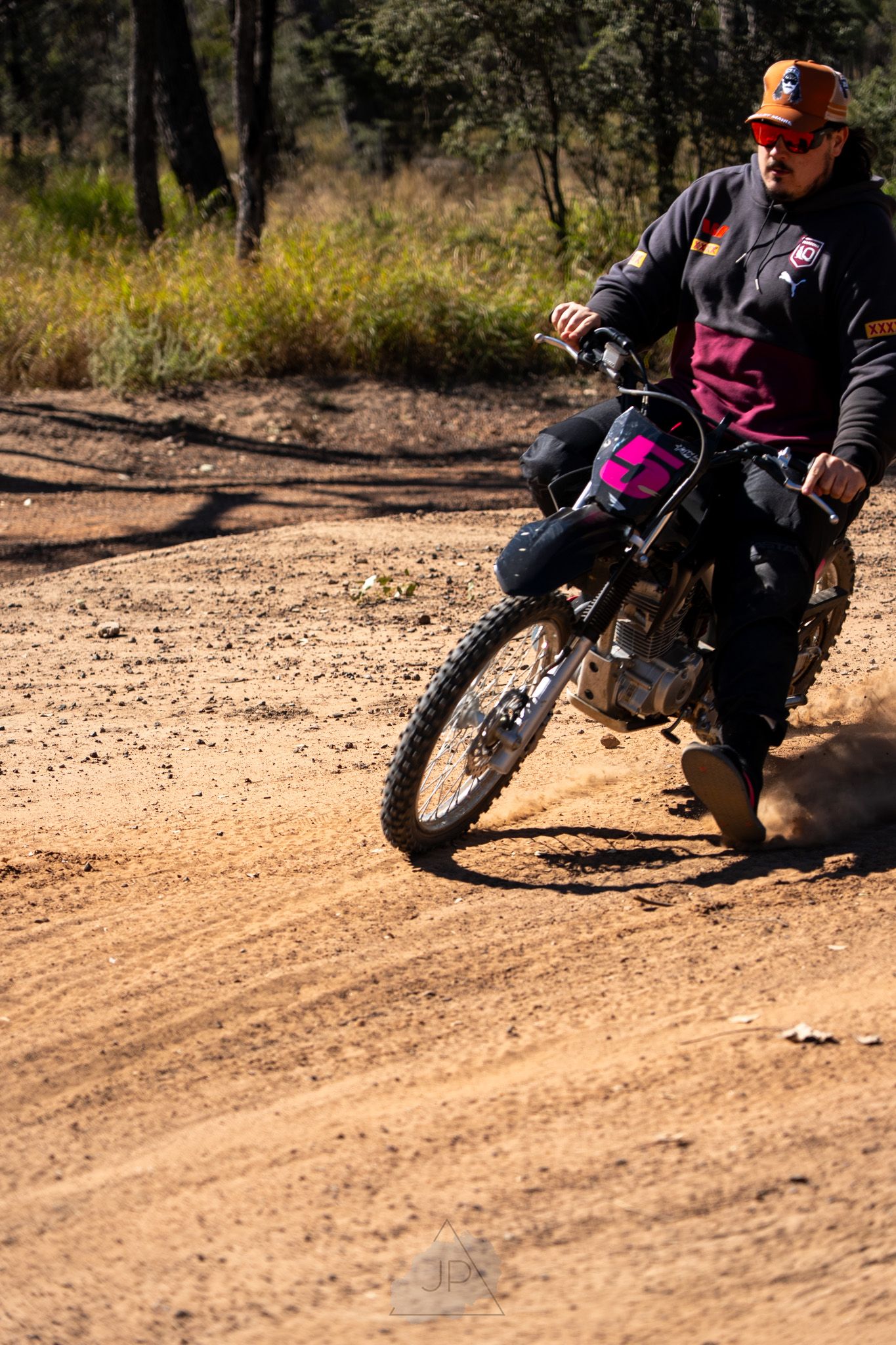 A dirt bike rider leans into a turn on a dusty trail while practicing motorcycle riding skills on an off-road course.