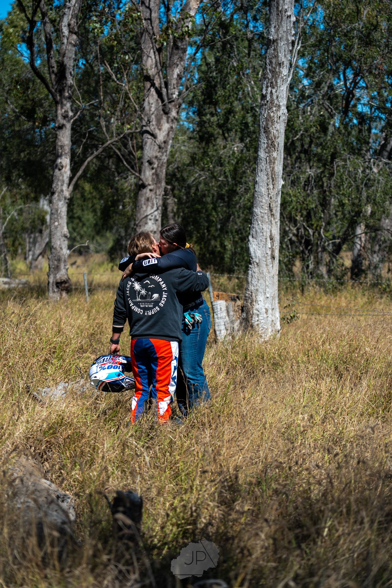 Mountain biker takes a break while resting among eucalyptus trees on a grassy hillside trail.