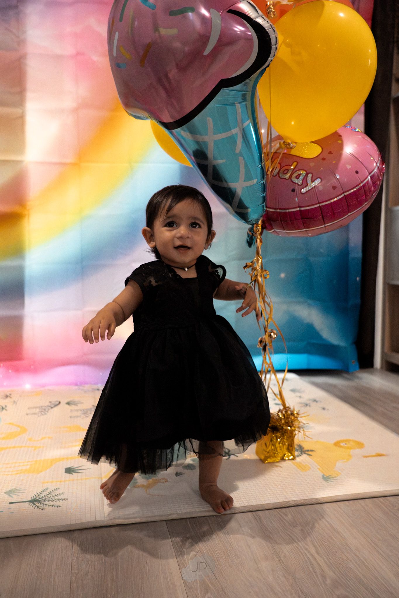 A sequence of photos showing a small child in a black tutu dress dancing and playing with colorful balloons.
