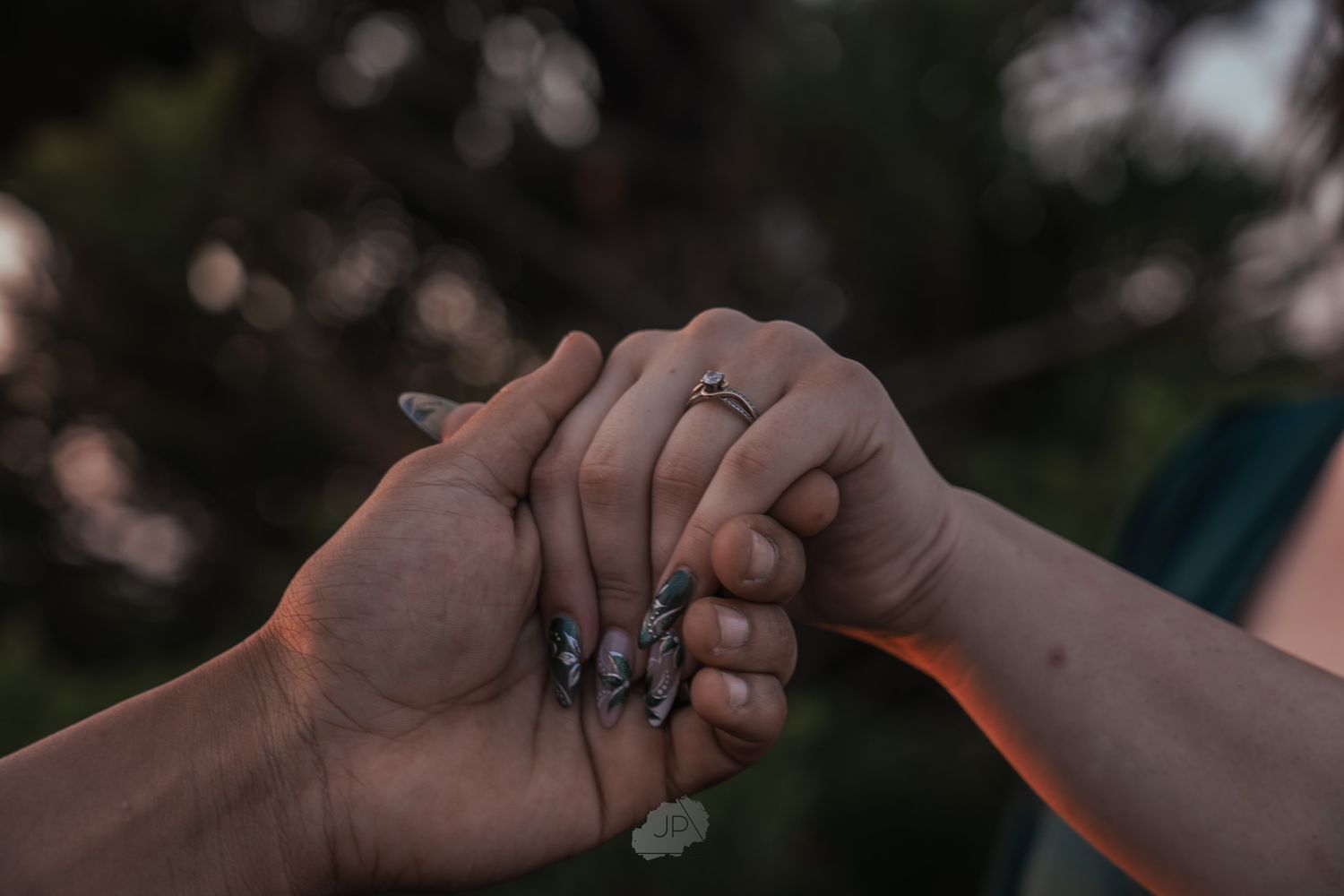 A close-up shot of hands holding each other in a supportive gesture against a blurred outdoor background.