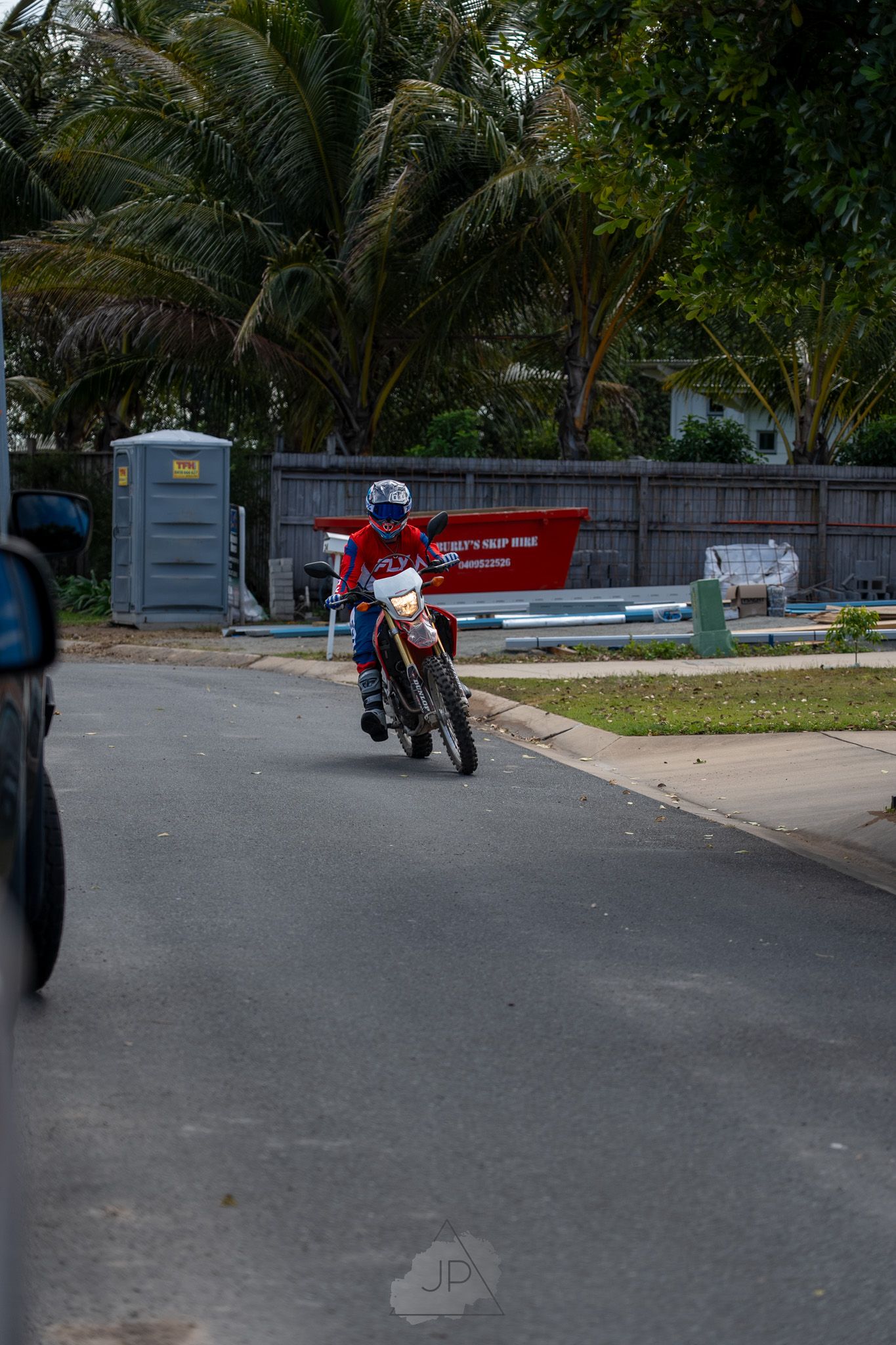 Street scene with palm trees and parked motorcycles on an empty suburban road.