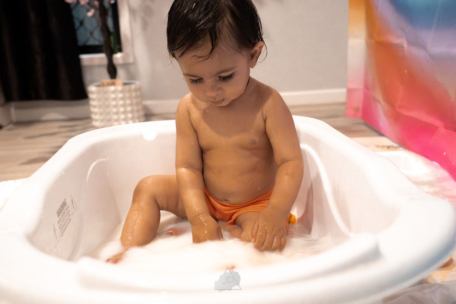 A baby playing in a bathtub with colorful toys and bubbles, creating a joyful bathtime experience.