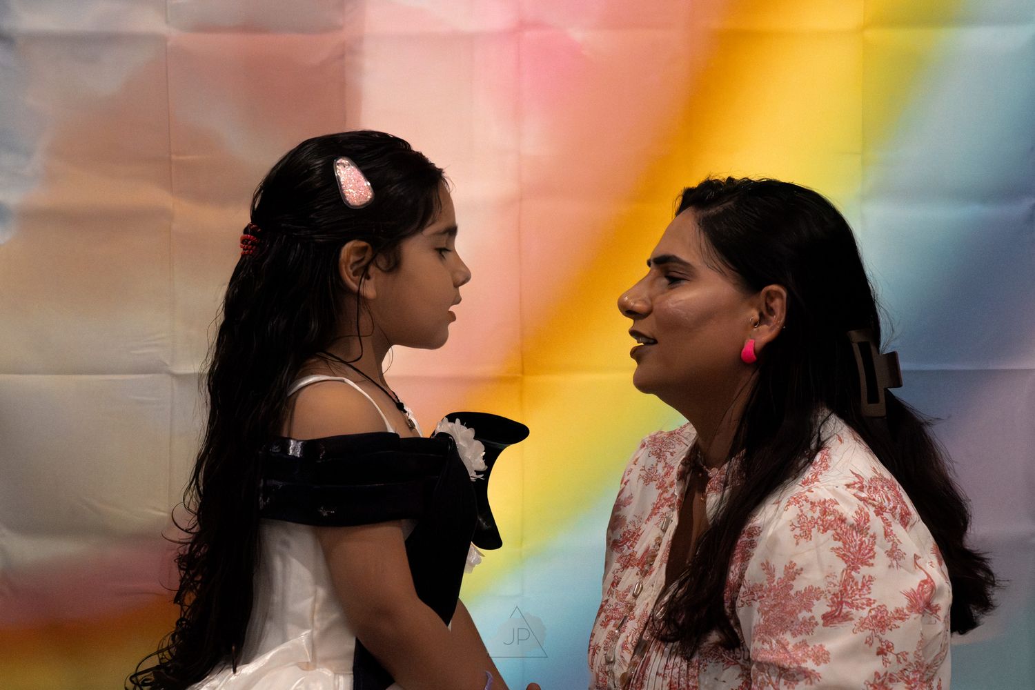 Two women share a romantic moment under colorful lighting during what appears to be a wedding celebration.