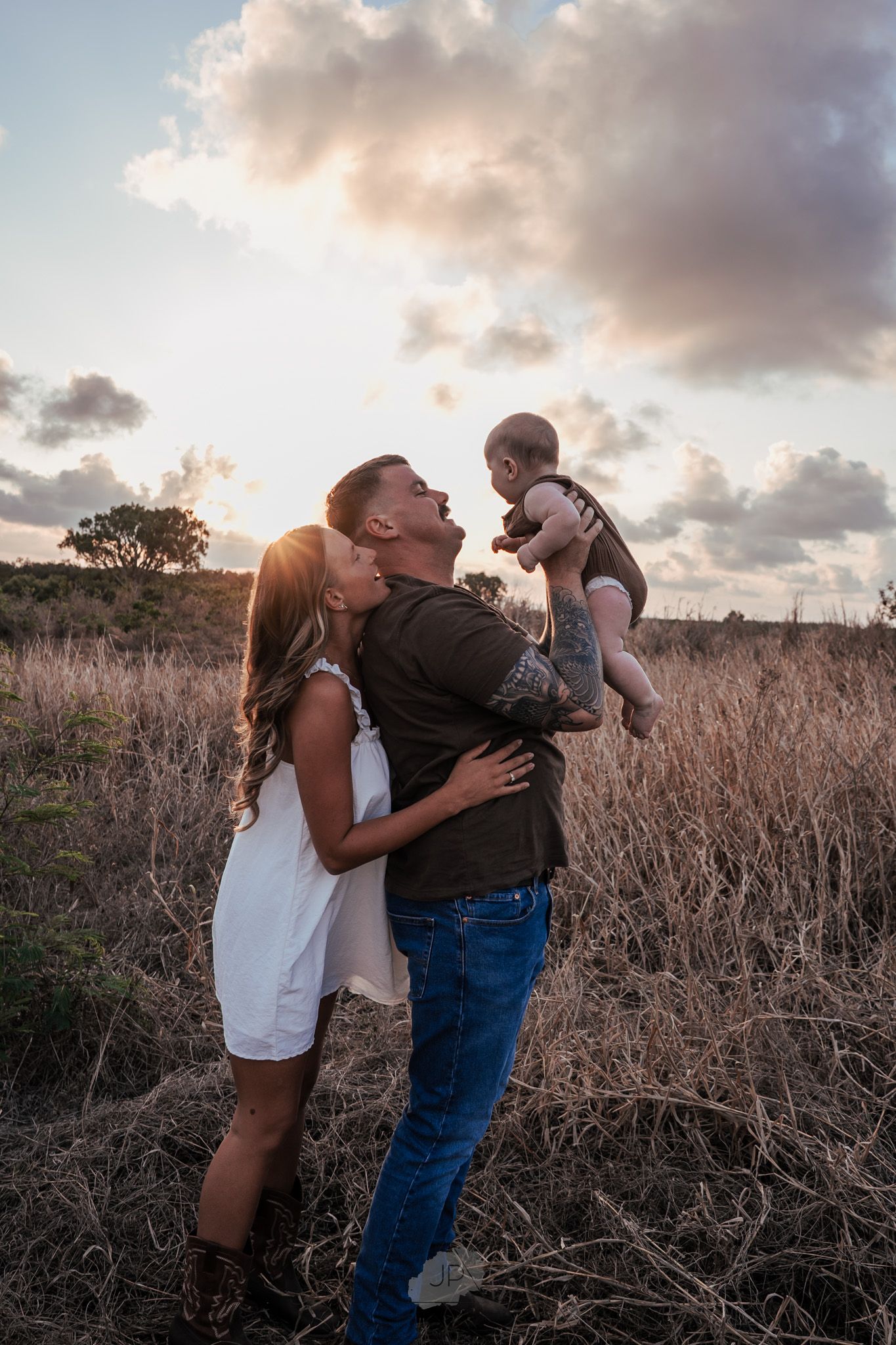 A couple shares intimate moments in a field of dried grass during sunset, captured in a series of romantic poses.