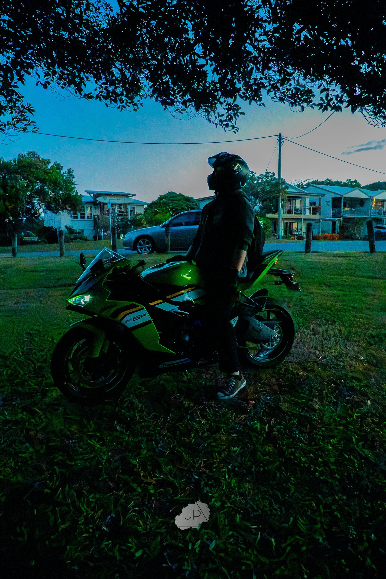 A custom neon green motorcycle parked on grass in twilight creating a striking silhouette against the evening sky.
