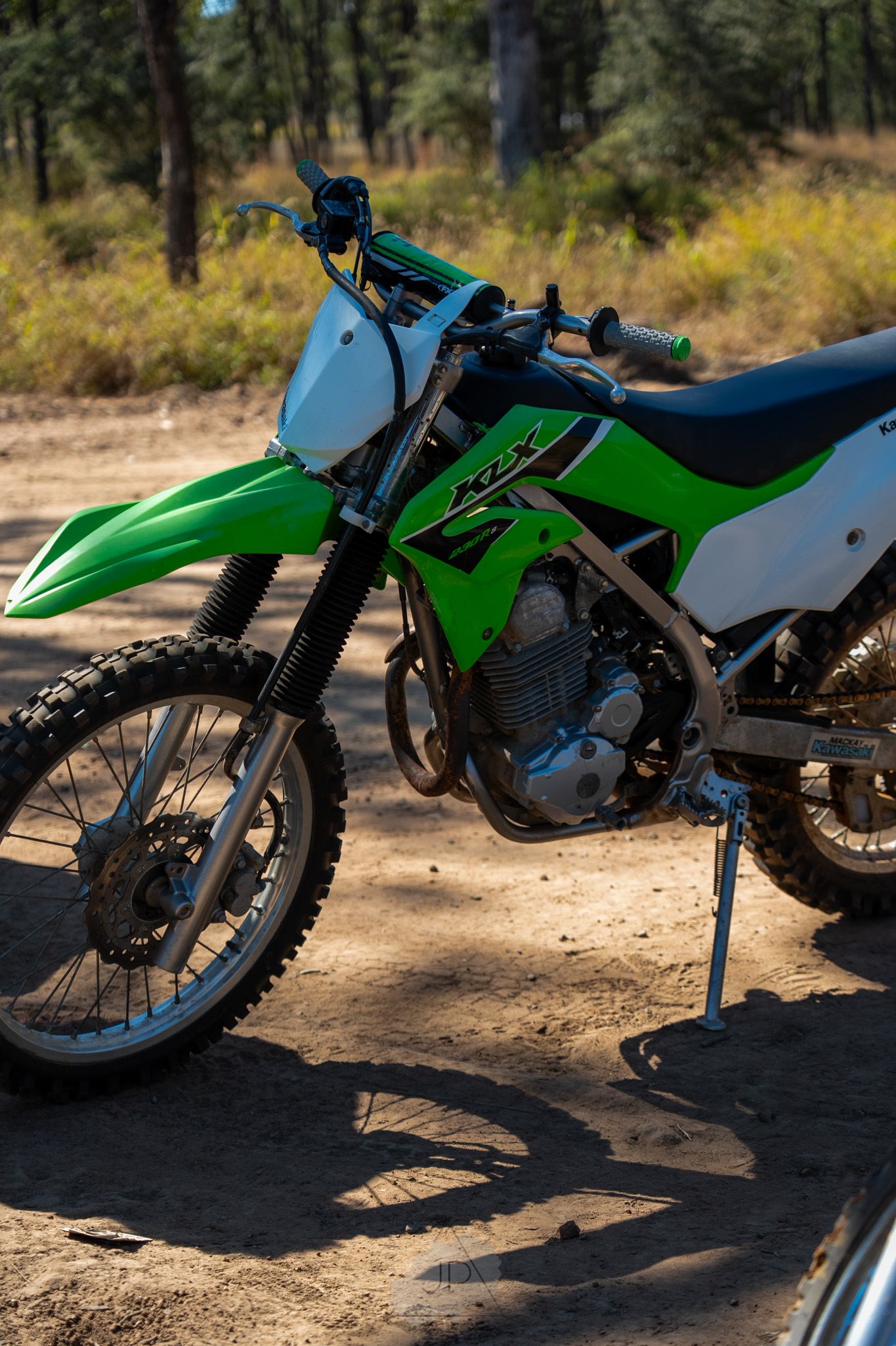 A series of close-up shots showing different angles of a green and white off-road dirt bike parked in a forest setting.