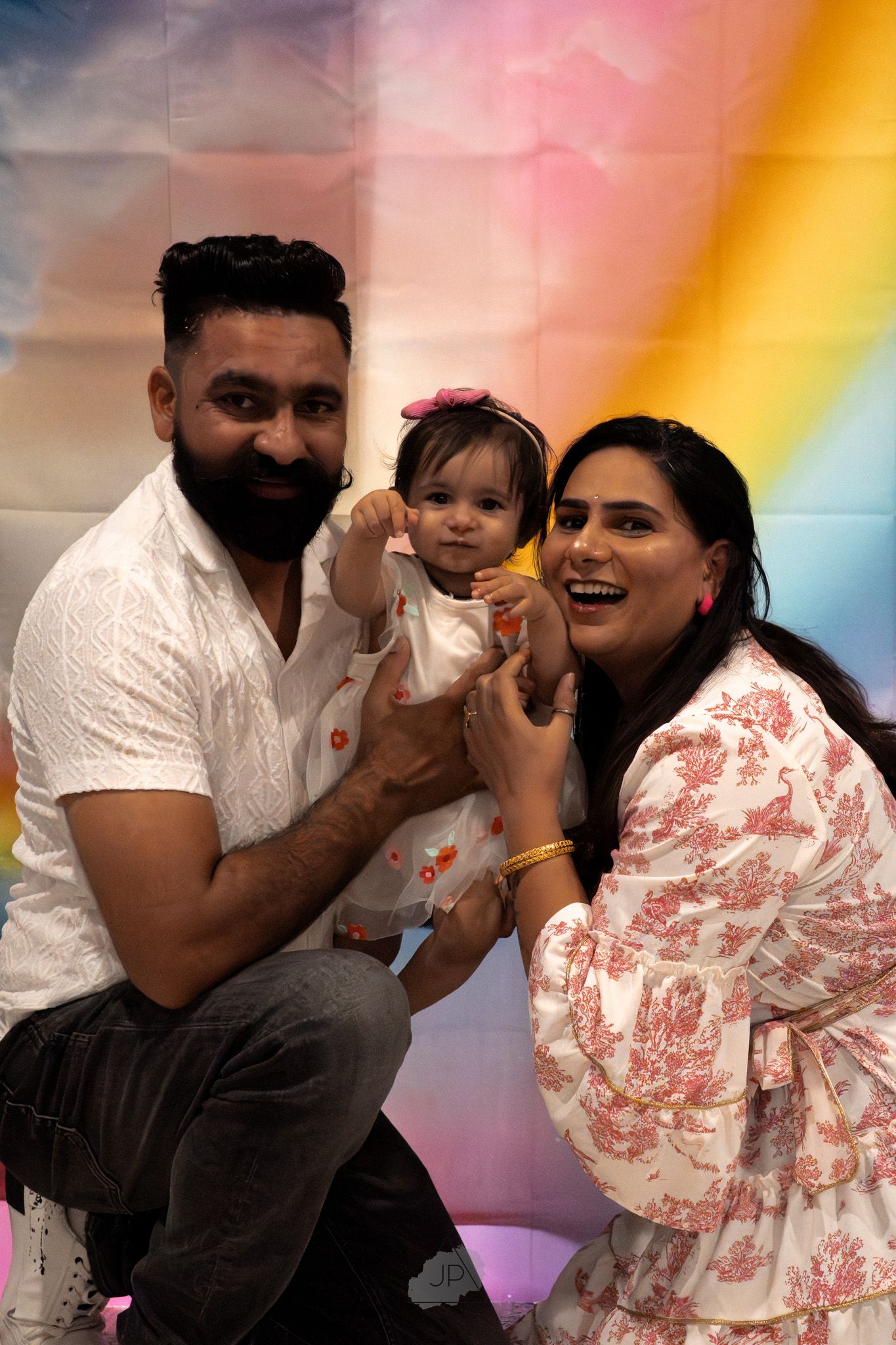A family shares playful moments together against a colorful rainbow background in a photo series.