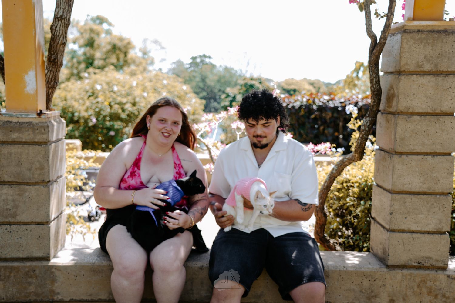 A group of people sitting on stone benches in an outdoor garden setting during a sunny day.