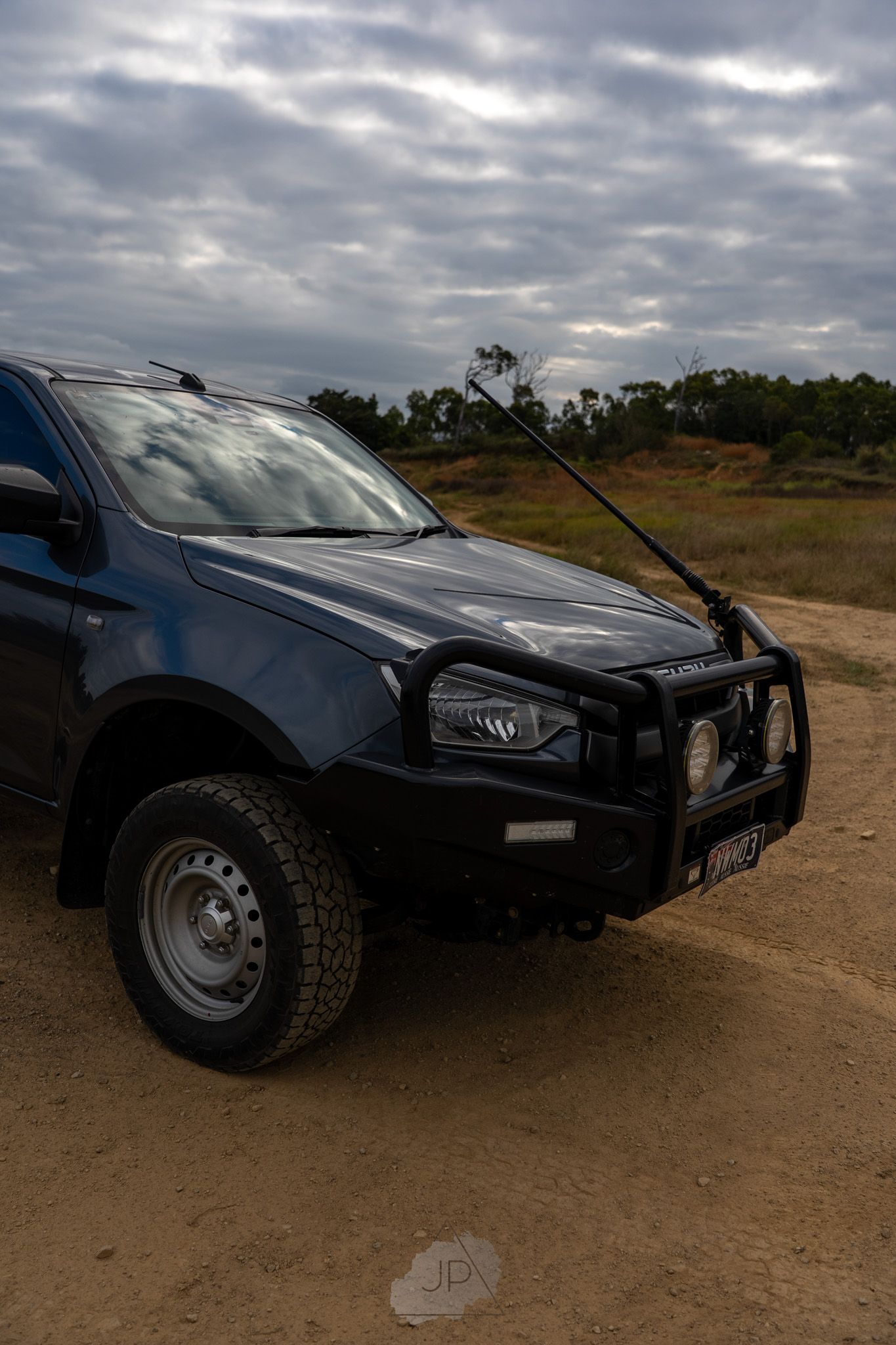 Modified black truck with custom off-road bumper and wide tires shown from multiple angles on dirt terrain.