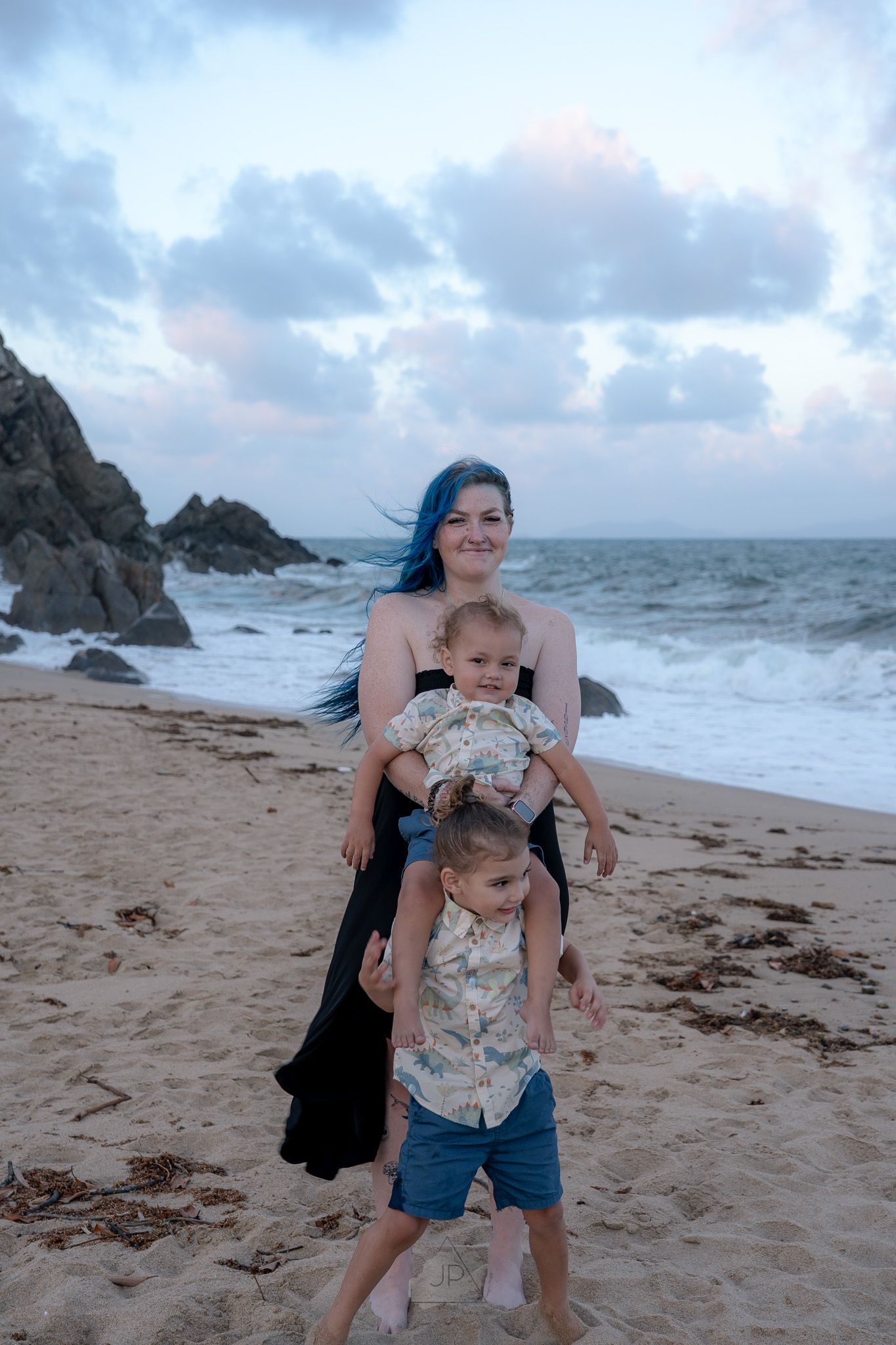 Family enjoying a fun day at the beach with stormy waves and rocky cliffs in the distance.