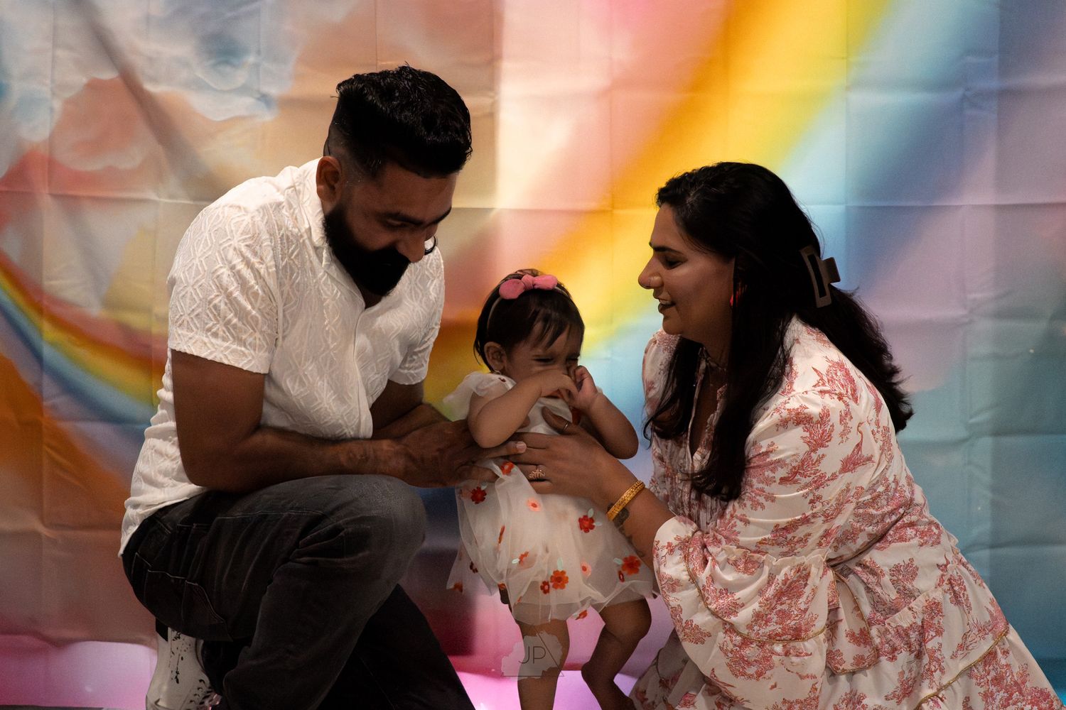 A loving family shares tender moments together against a colorful rainbow backdrop.