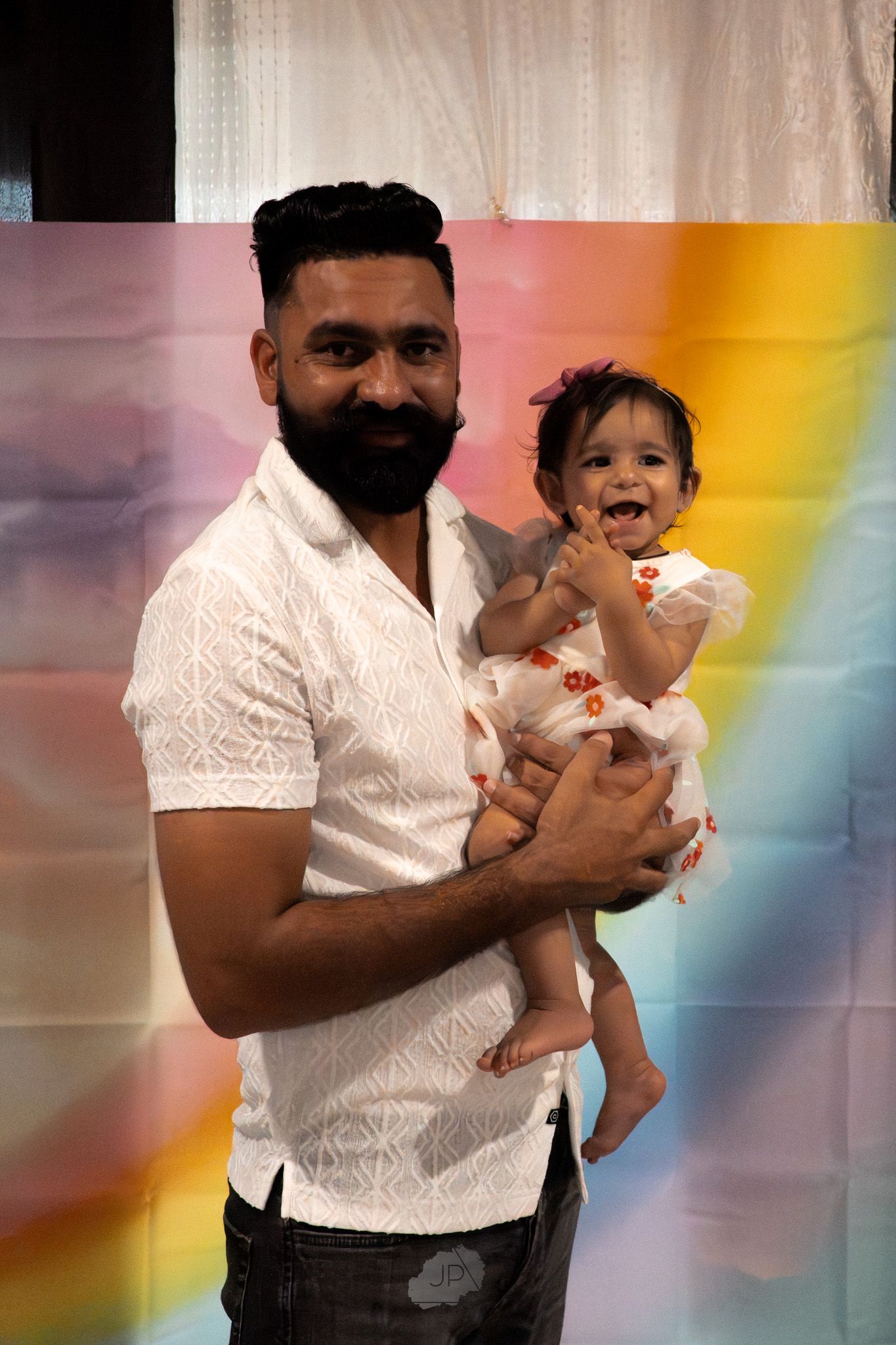 A sequence of joyful moments captured between two people in white outfits with a rainbow-colored backdrop.