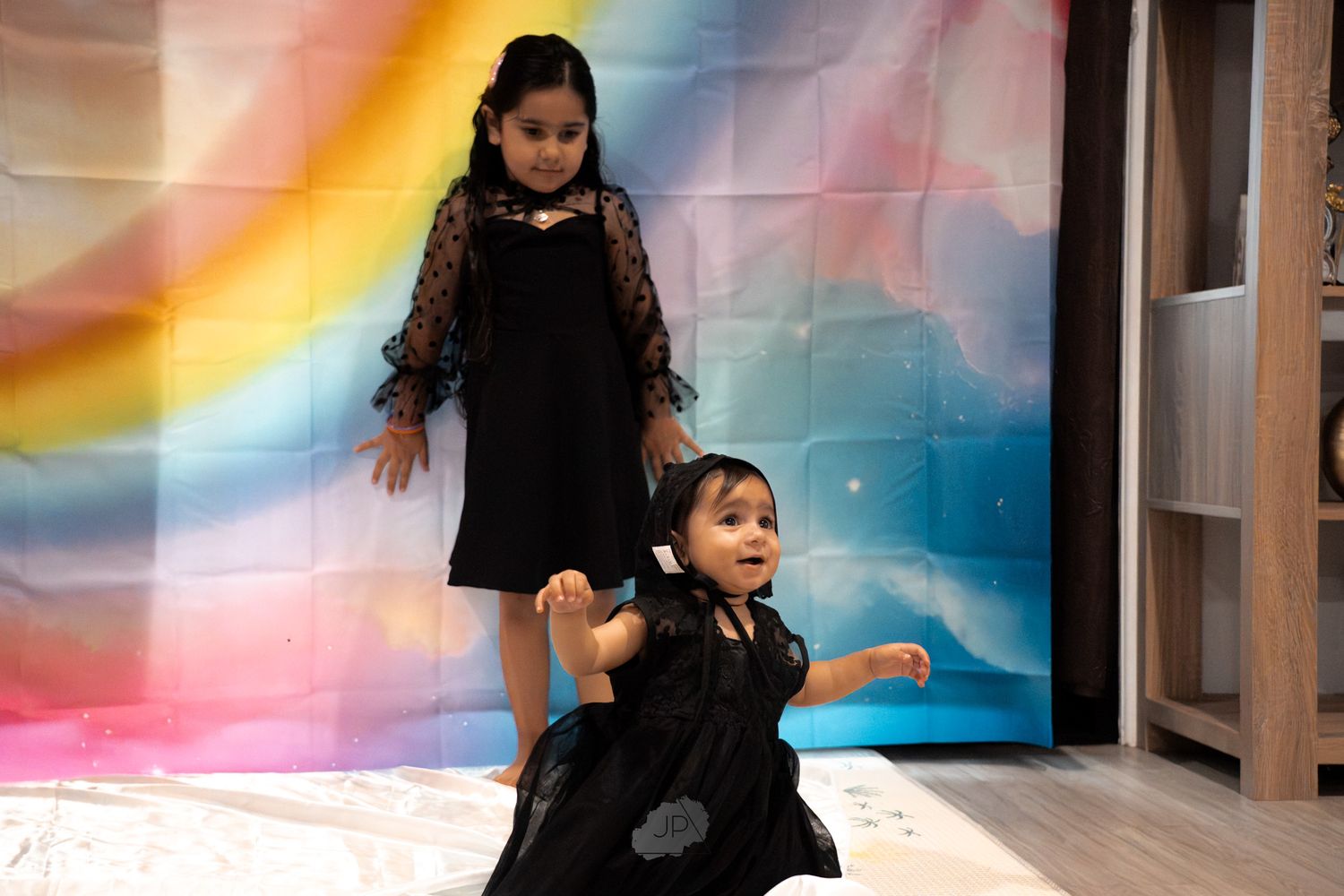 A group of children dance and play together in a brightly lit room with colorful rainbow reflections on the walls.
