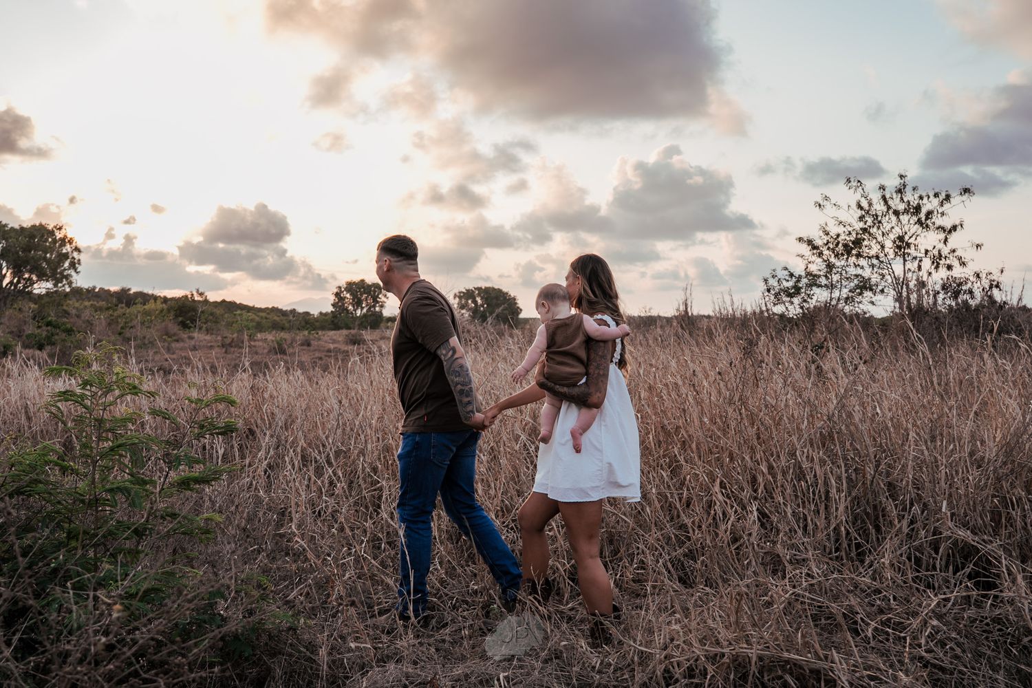 A couple embraces in a golden field during sunset creating a romantic silhouette against the warm sky.