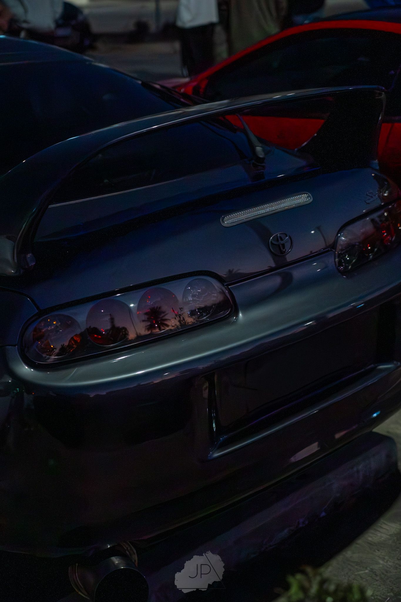 Classic vintage convertible car with sleek chrome trim and dark paint shown at dusk.