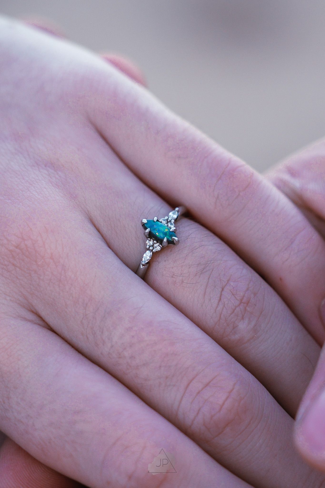 Close-up view of an elegant turquoise and diamond engagement ring on a person's hand.