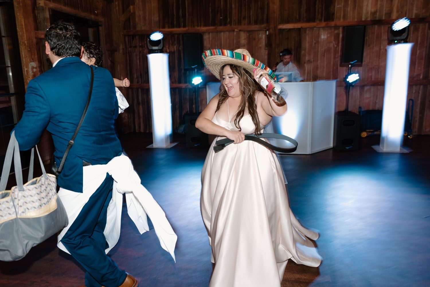 Couple dances together in rustic wooden barn venue during romantic first dance at wedding reception.
