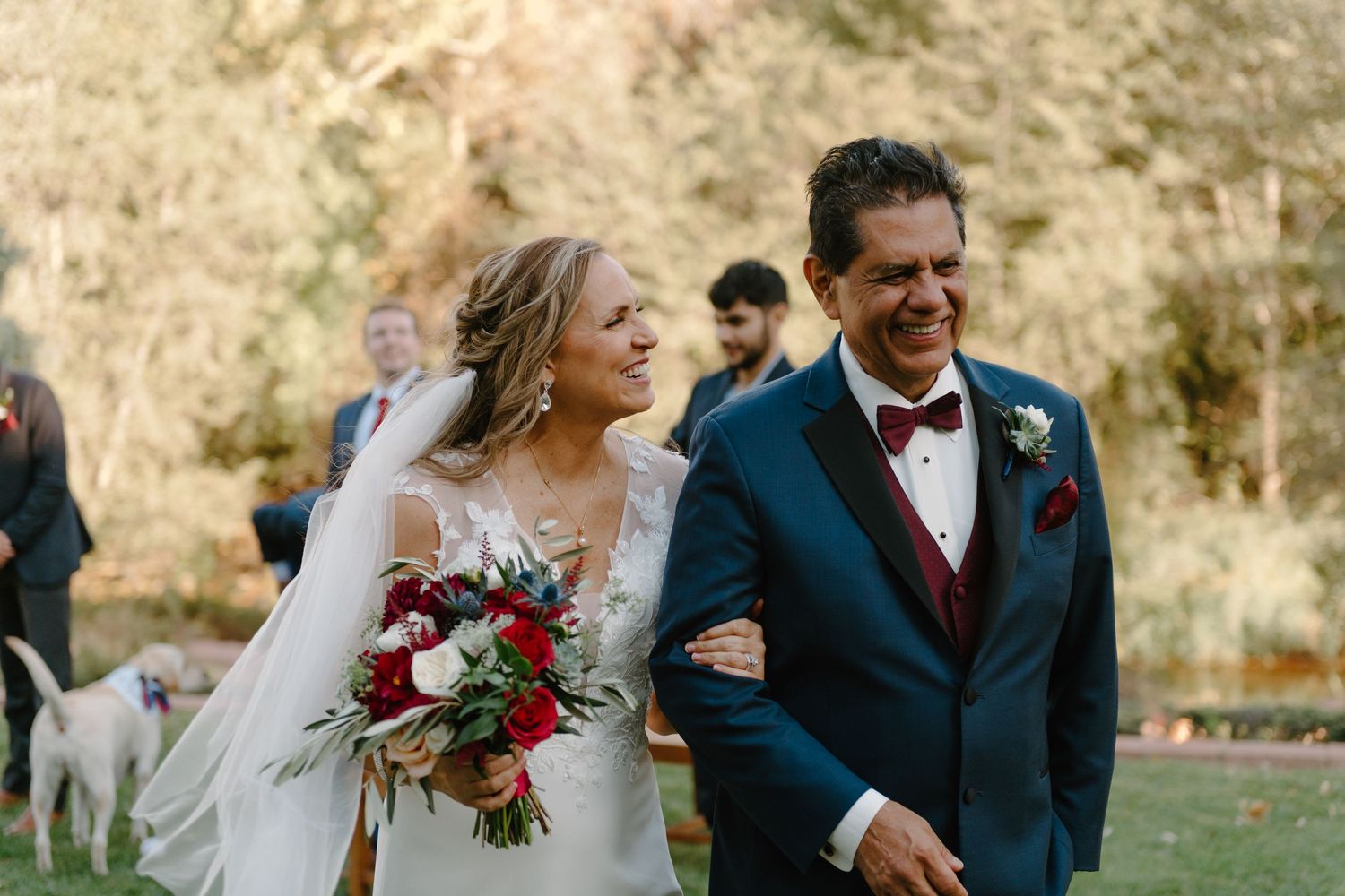 A couple shares joyful moments during their wedding celebration in a scenic outdoor setting with autumn colors.