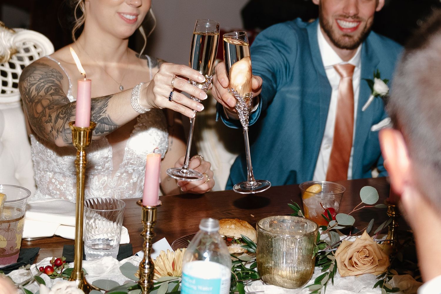 Wedding guests raise champagne glasses during an elegant reception toast at a formal dinner celebration.
