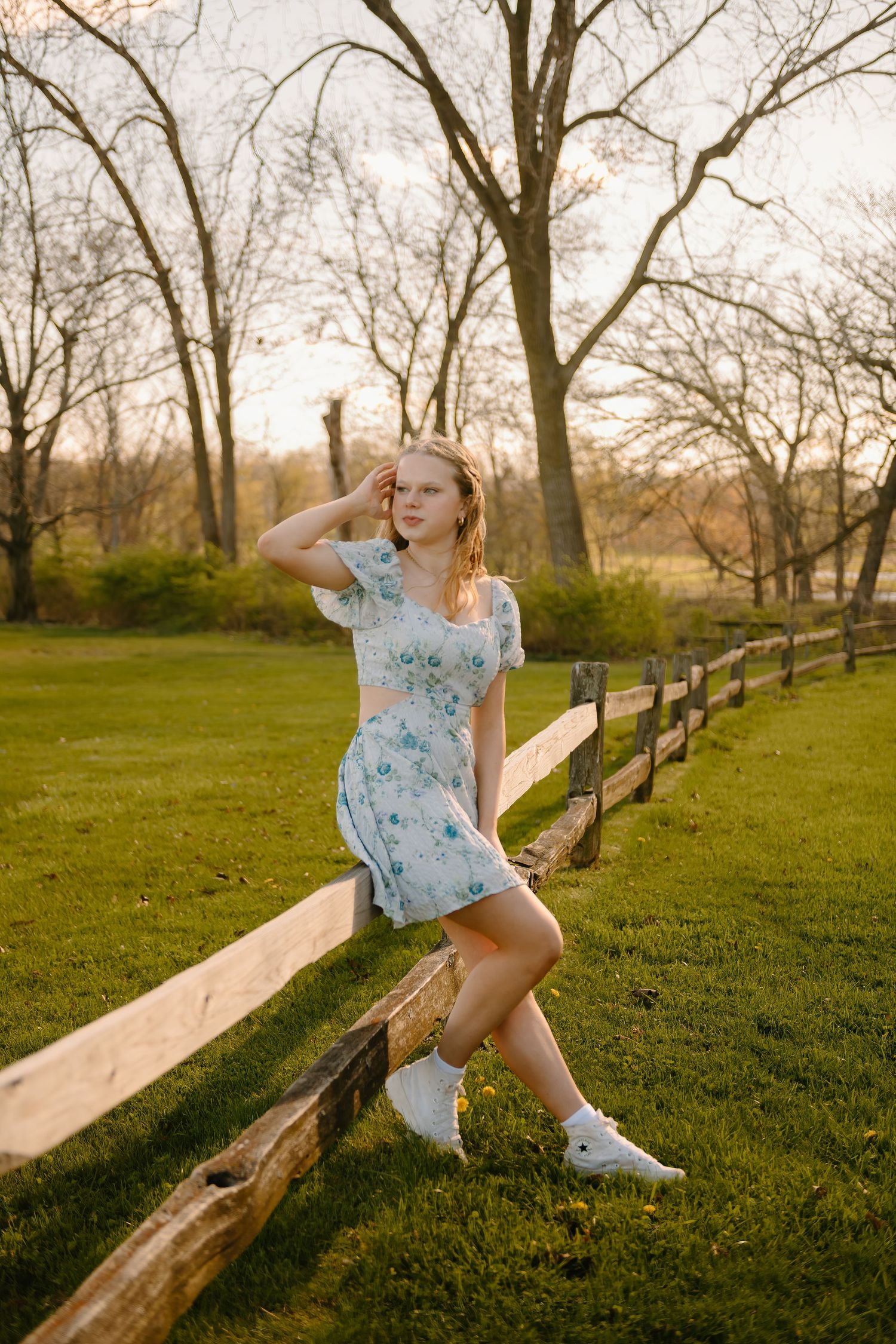 A sequence of photos shows a person in a floral dress sitting and jumping on a wooden fence in a grassy field at sunset.