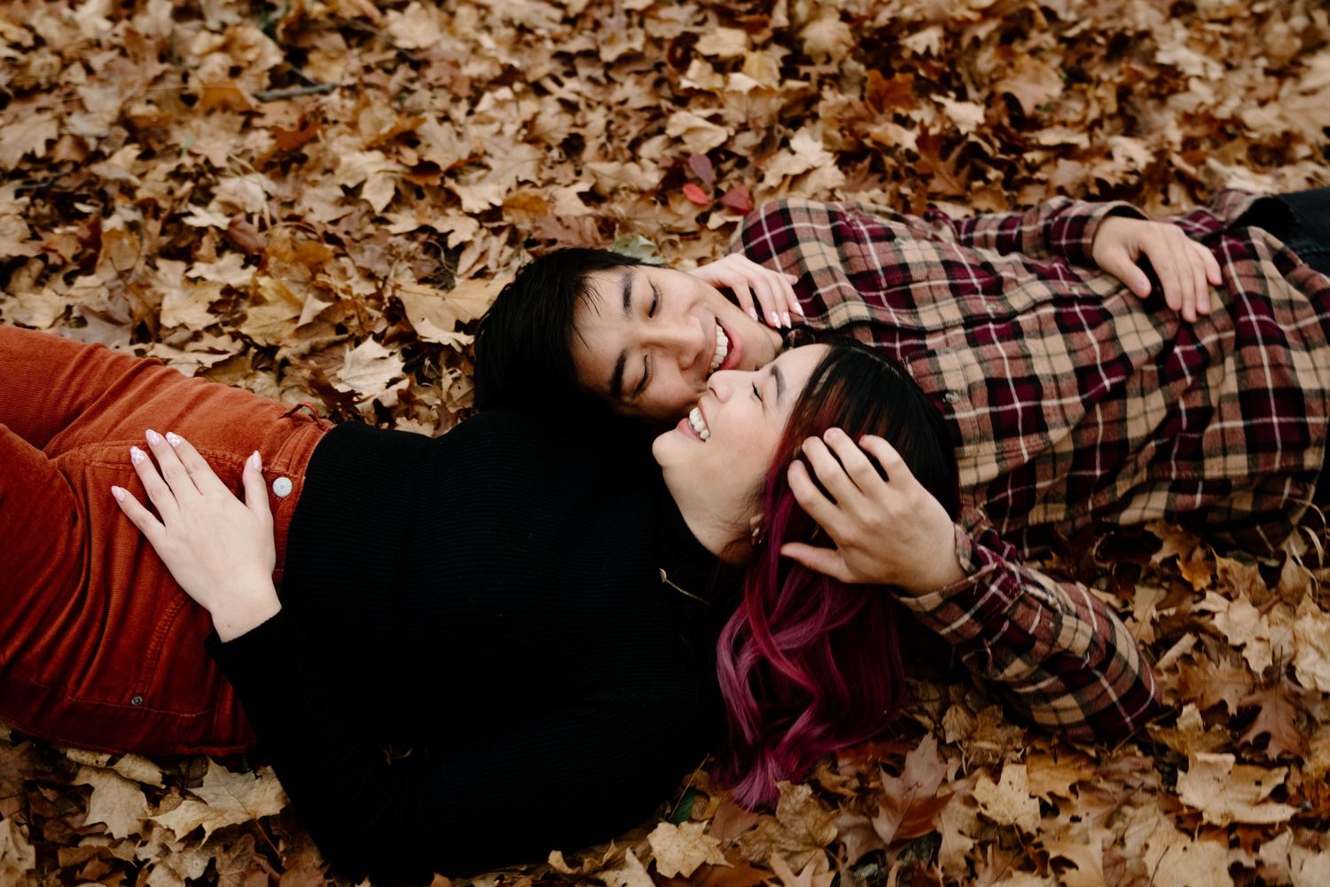 A series of romantic fall portraits showing a couple lying together among scattered autumn leaves in warm tones. Couples Photos Desplaines