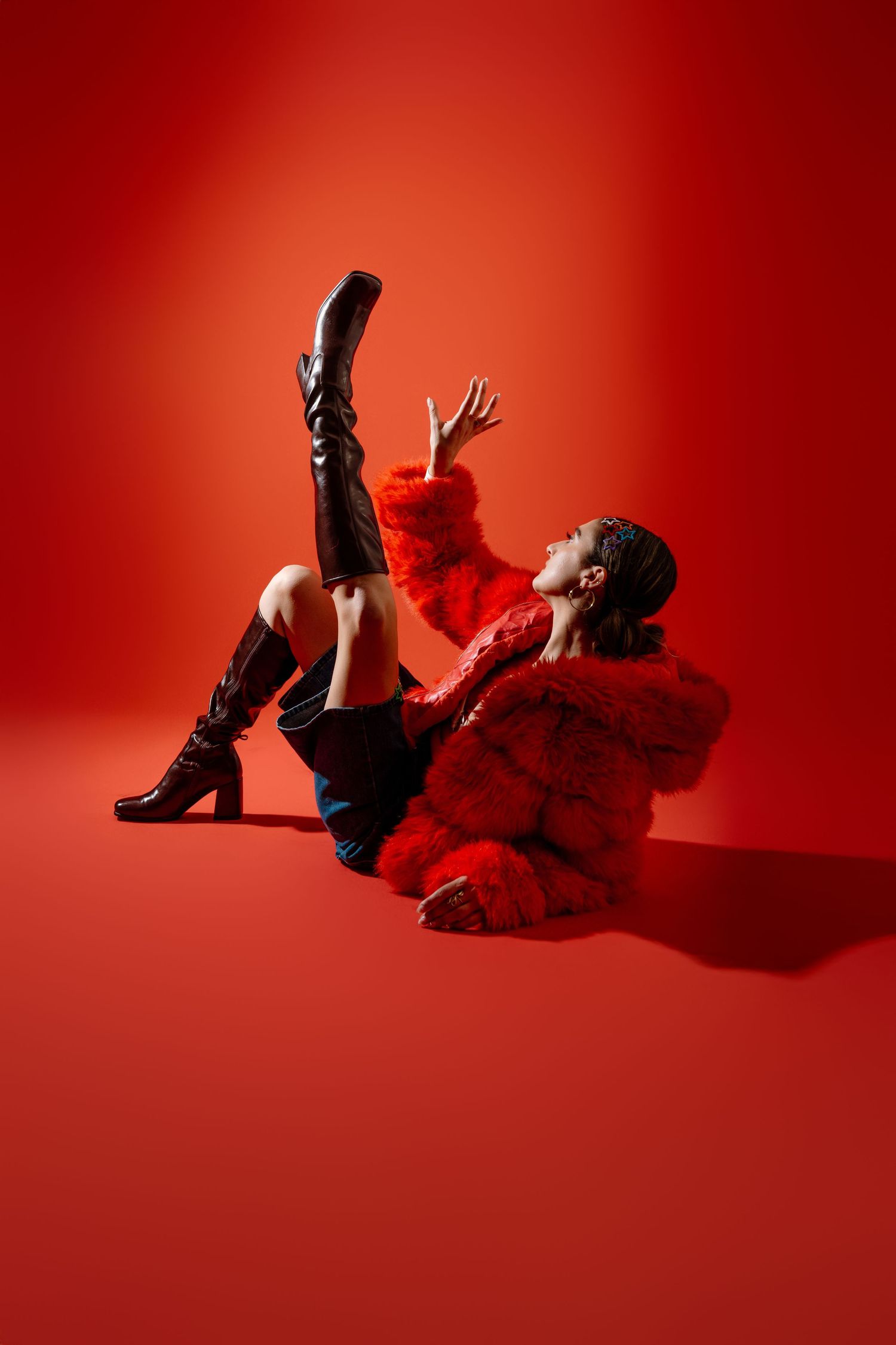 Four close-up shots show black boots and flowing red fabric against a vibrant red studio background.